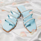 Stylera blue pearl strap sandals with multiple straps and pearl detailing on satin background
