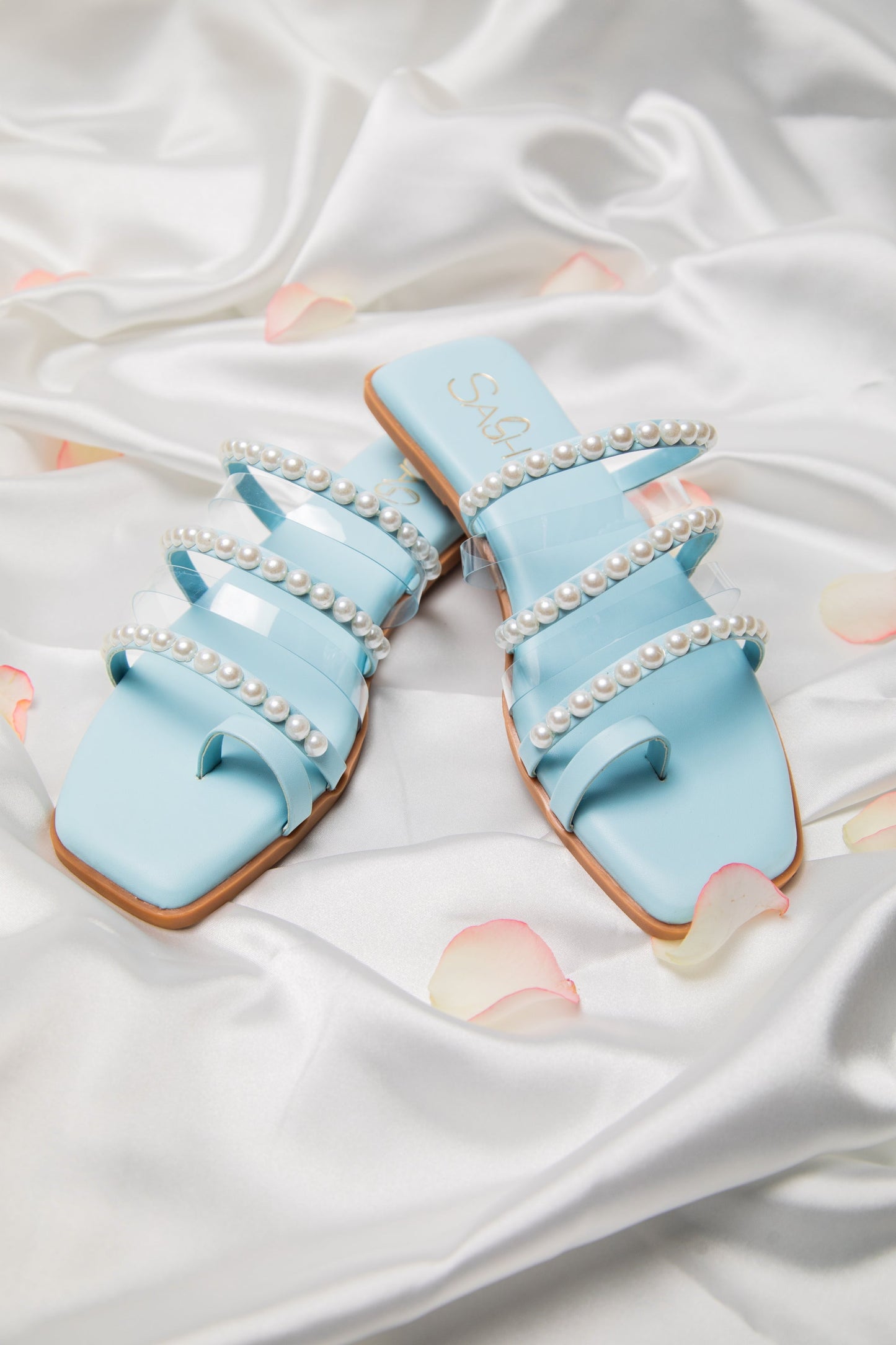 Stylera blue pearl strap sandals with multiple straps and pearl detailing on satin background