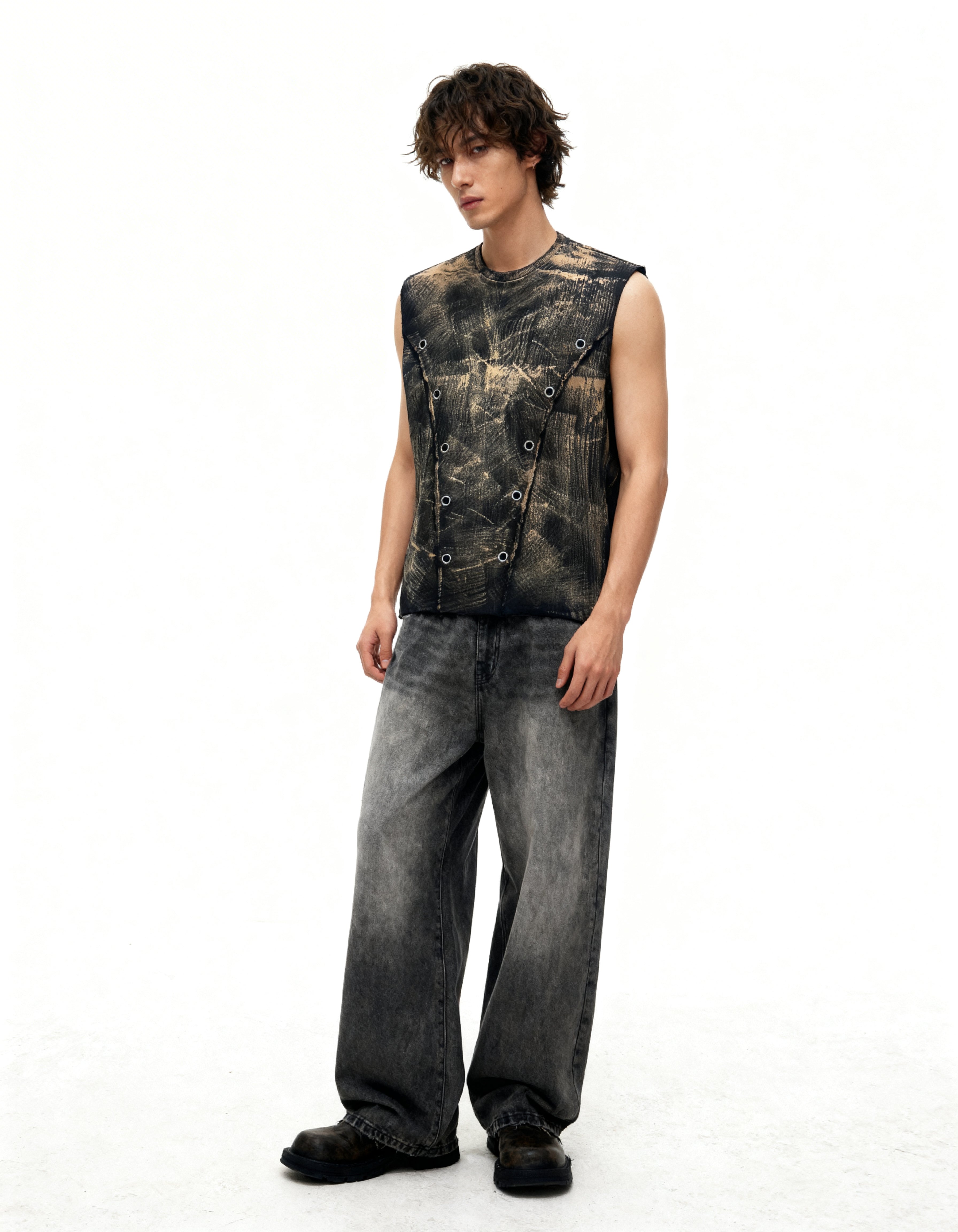 Person wearing a sleeveless studded leather vest and jeans on a white background