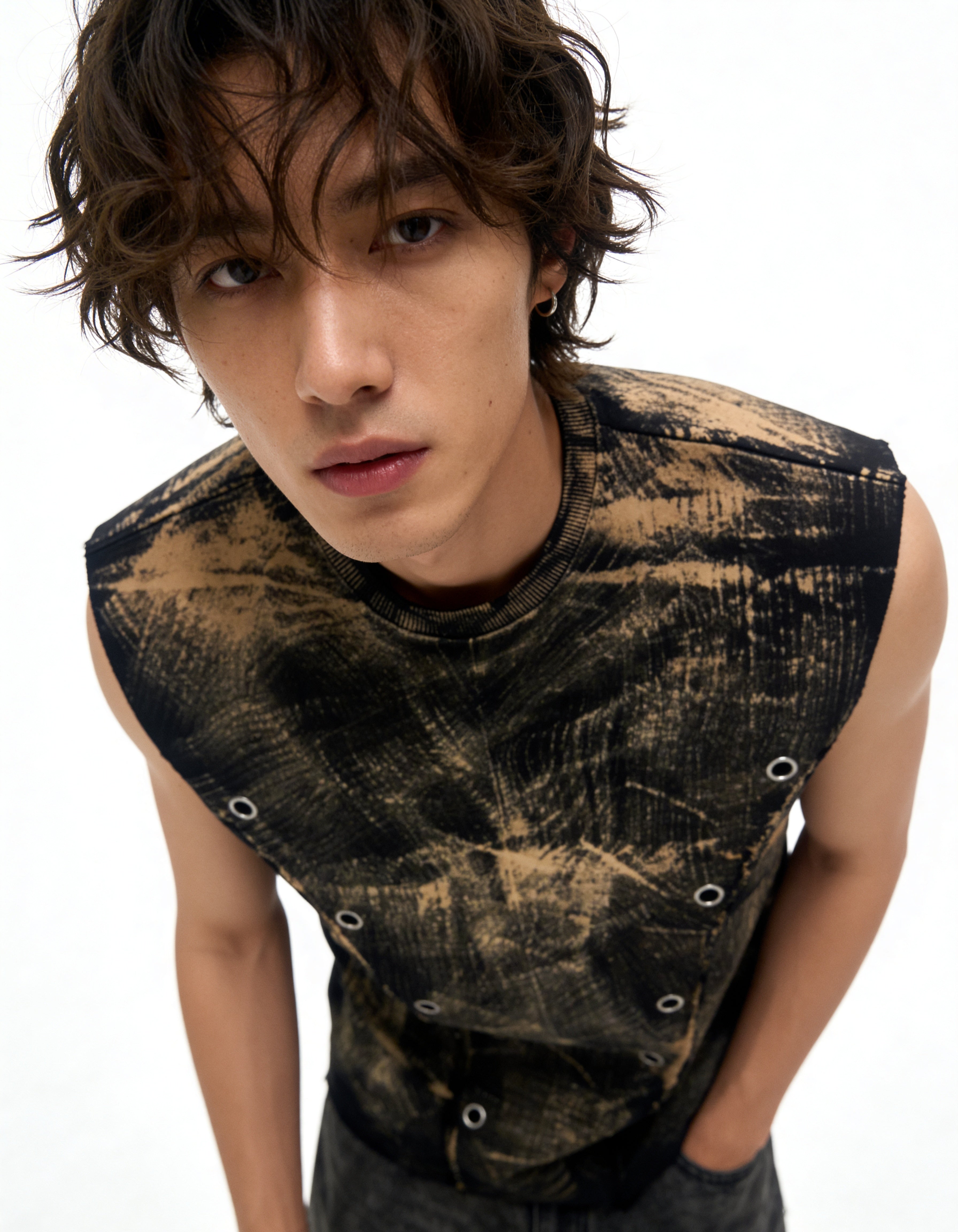 Person wearing a sleeveless, distressed black and gold top on a white background