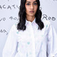 Model wearing Stylera white collared shirt with pastel motifs and ruffled sleeves stylish casual embroidered top