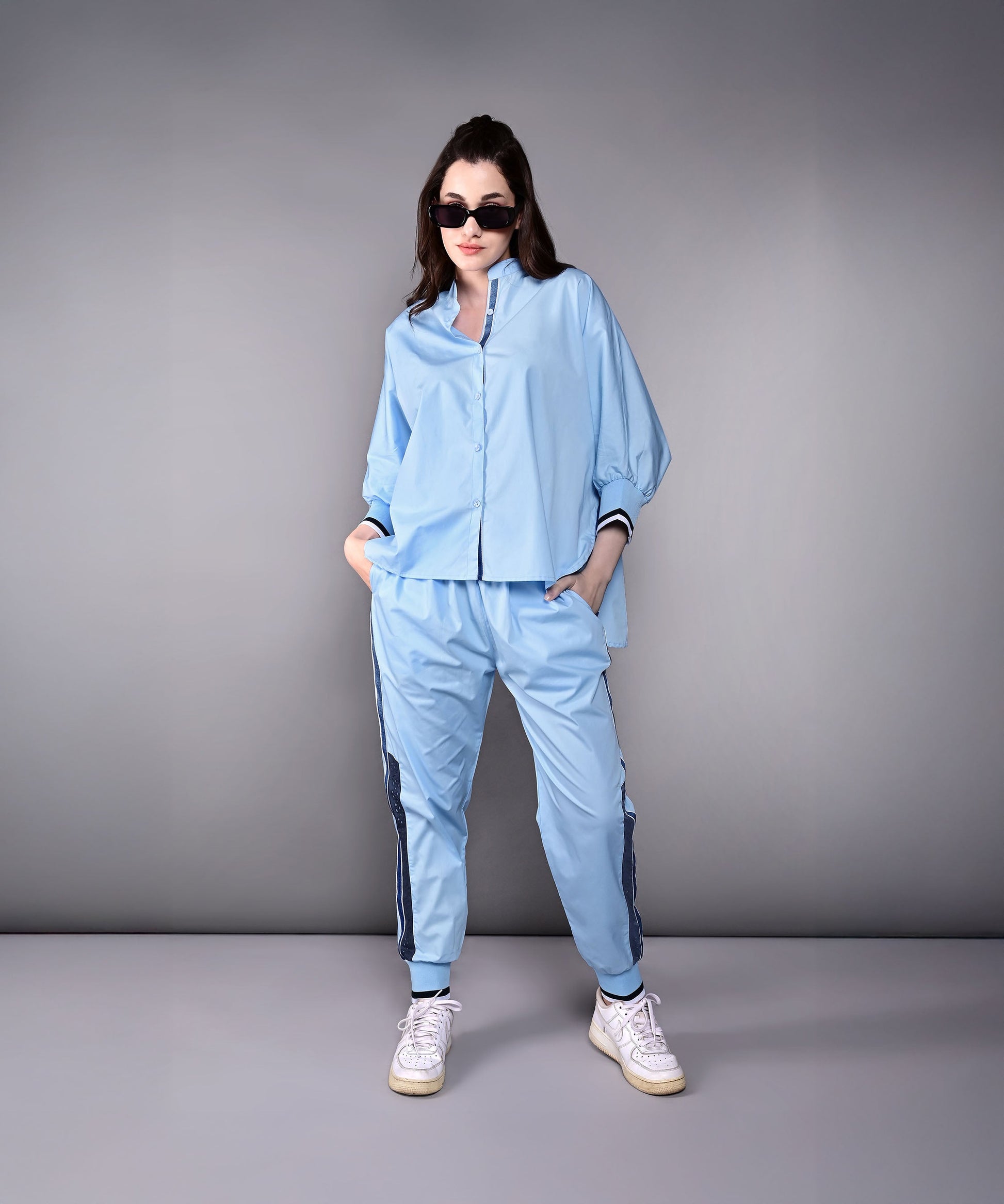 Model wearing a stylish denim track suit in light blue with sporty details and a relaxed fit