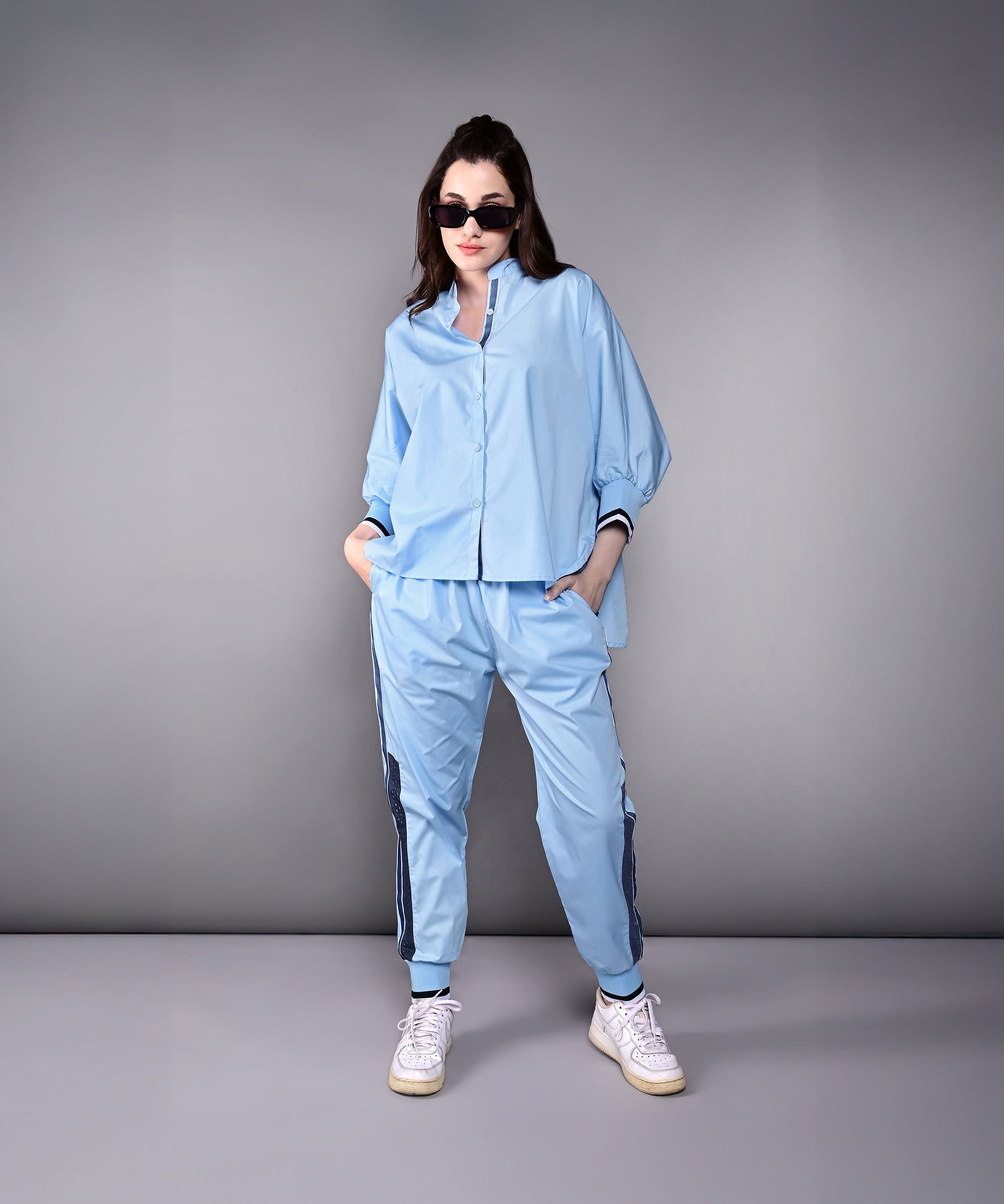Model wearing a stylish denim track suit in light blue with sporty details and a relaxed fit