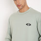 Stylera crewneck sage sweatshirt with small eye logo on chest worn by male model stylish graphic sweatshirts for camping