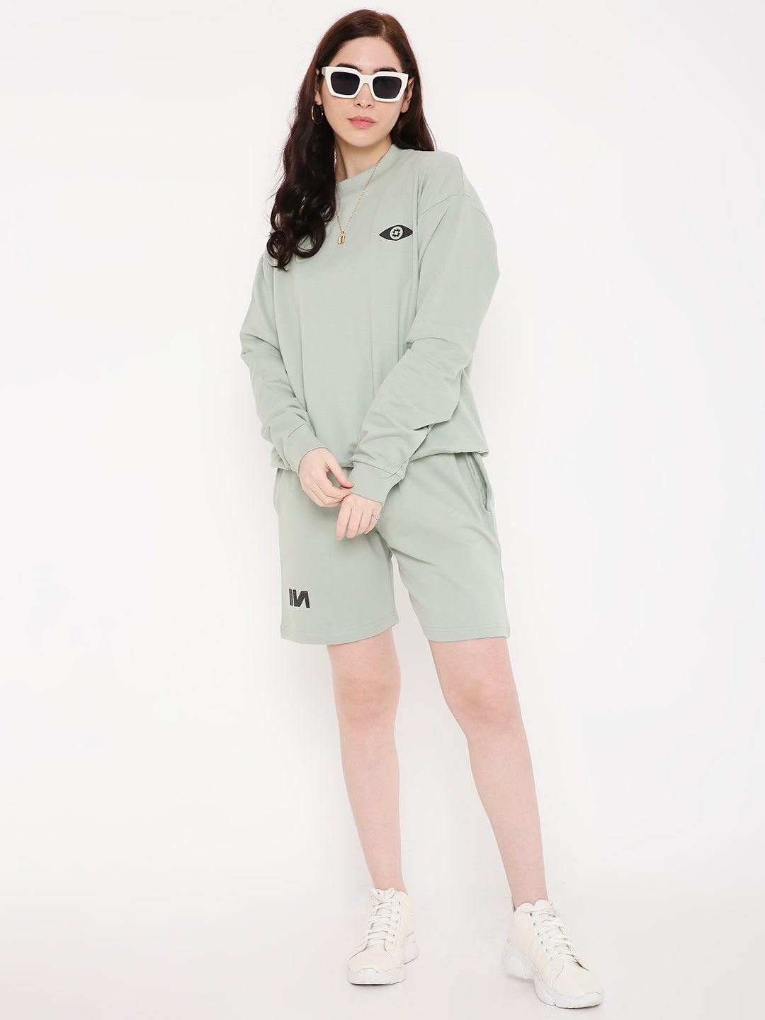Stylera sage green sweatshirt and shorts on model with white sneakers stylish graphic sweatshirts for camping
