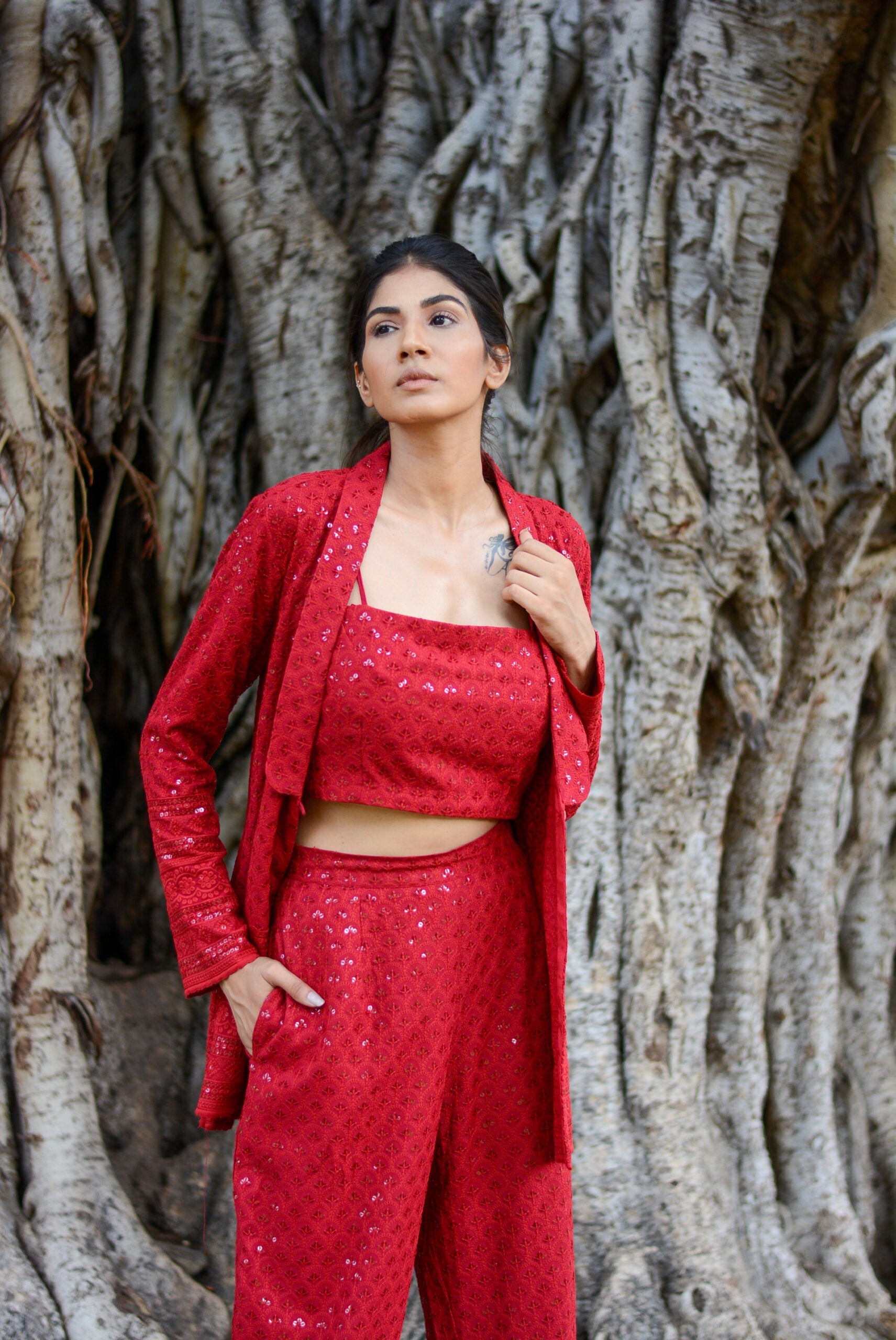 Model wearing a red stylish three piece set for parties with a matching top, pants, and jacket