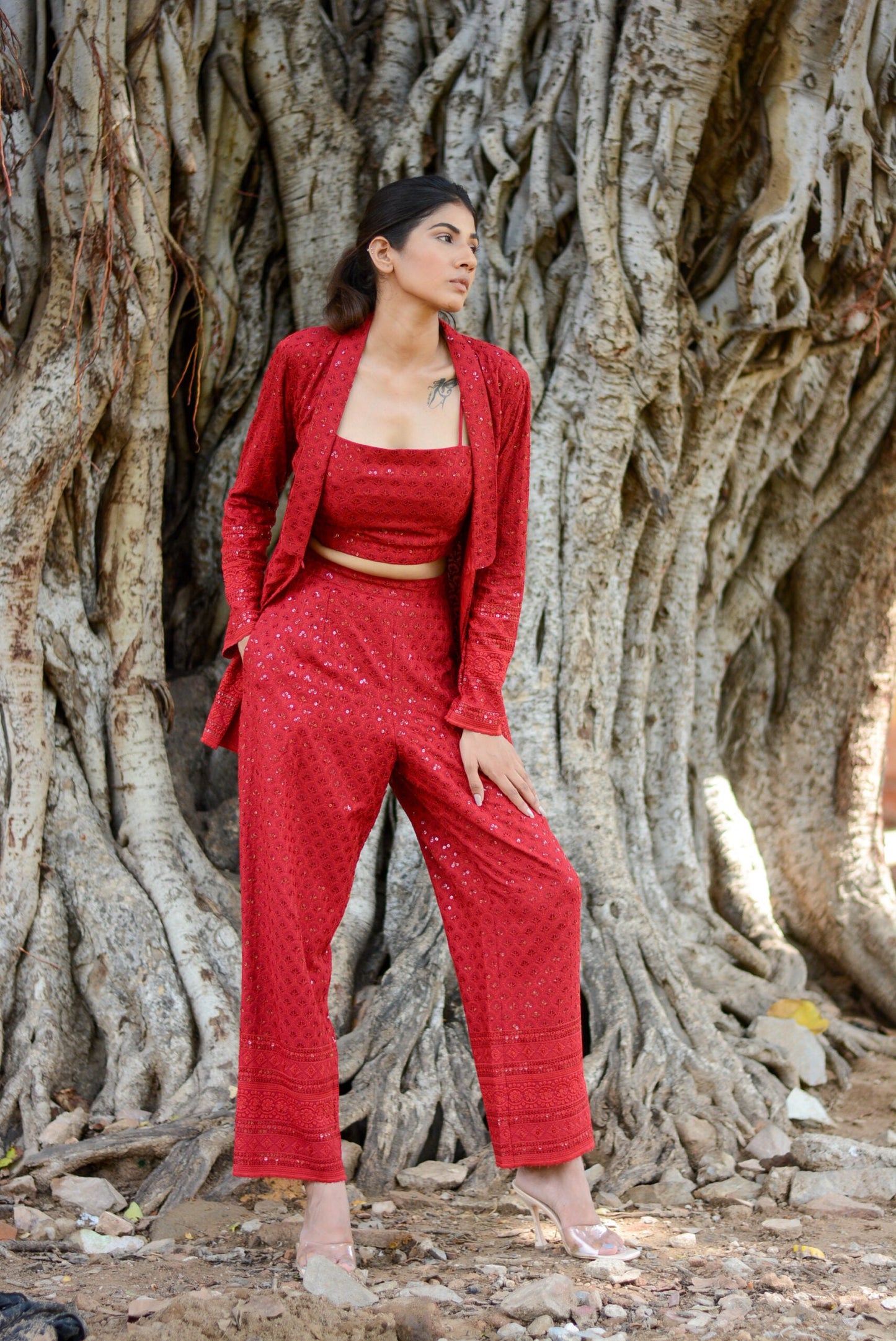 Model wearing a red stylish three piece set for parties with a crop top, jacket, and trousers
