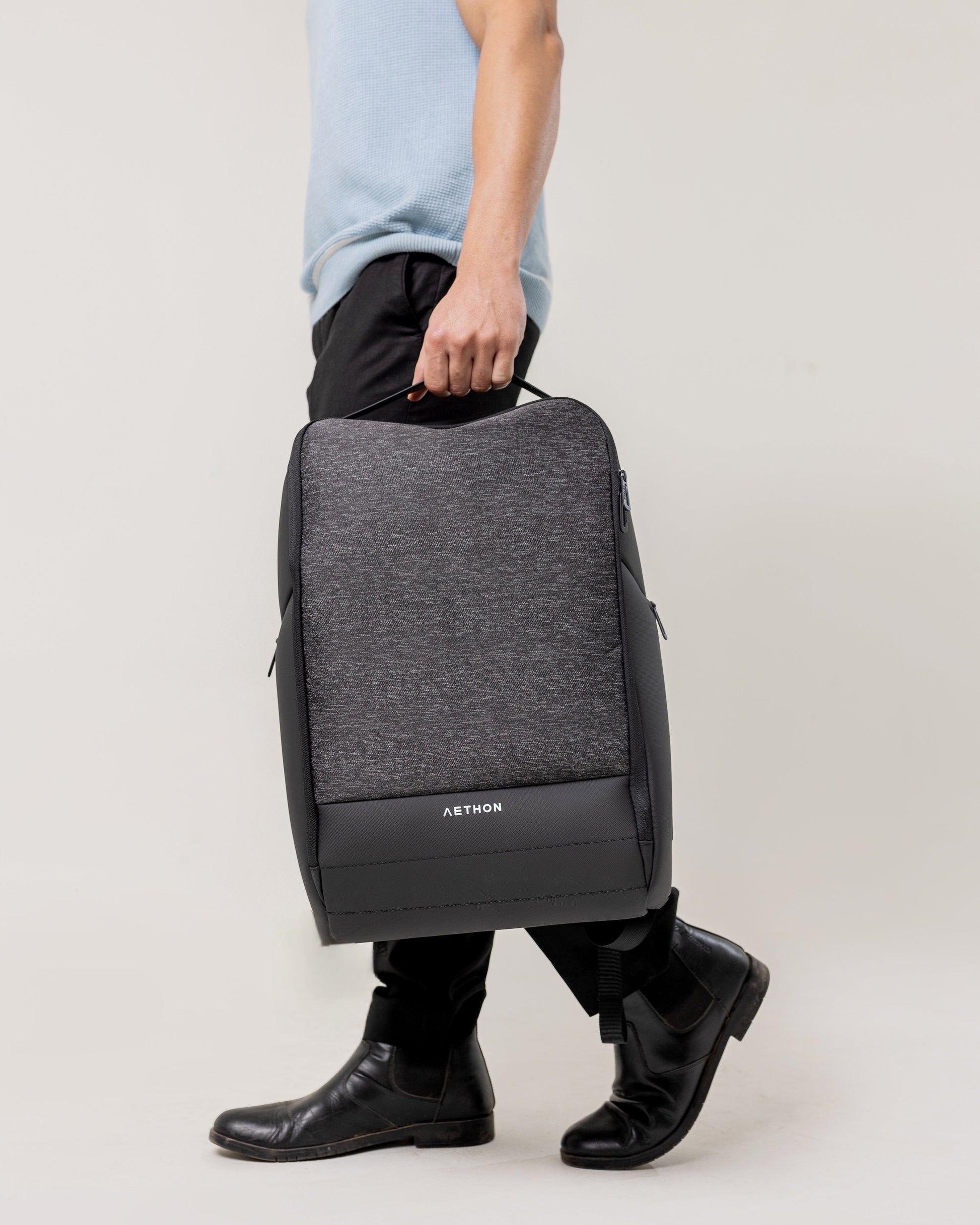 Stylera water resistant backpack with gray front panel and black trim held by a man as a stylish work backpack for men