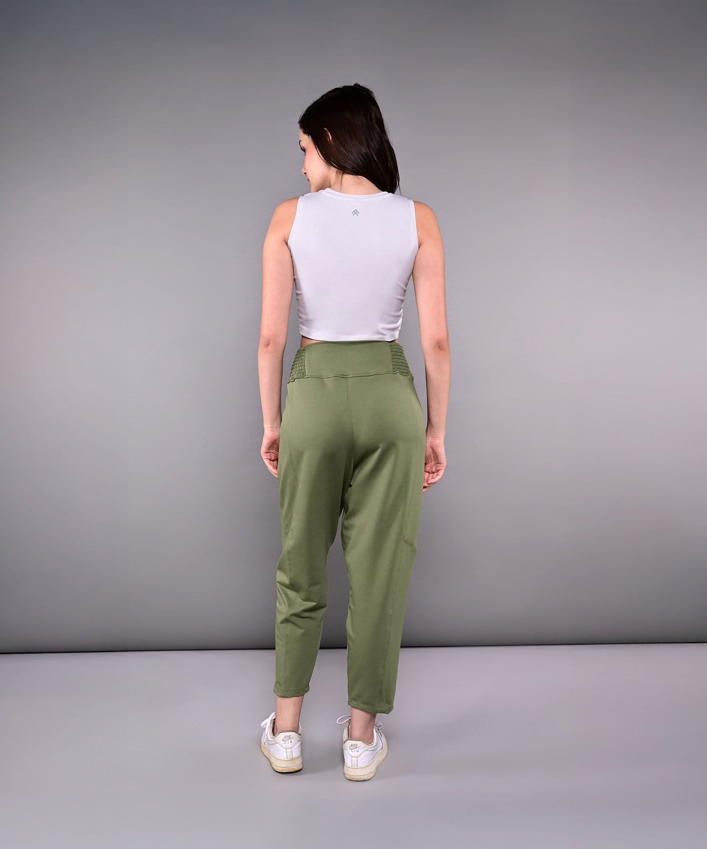 Back view of stylish yoga pants with pockets in olive green paired with a fitted gray tank top