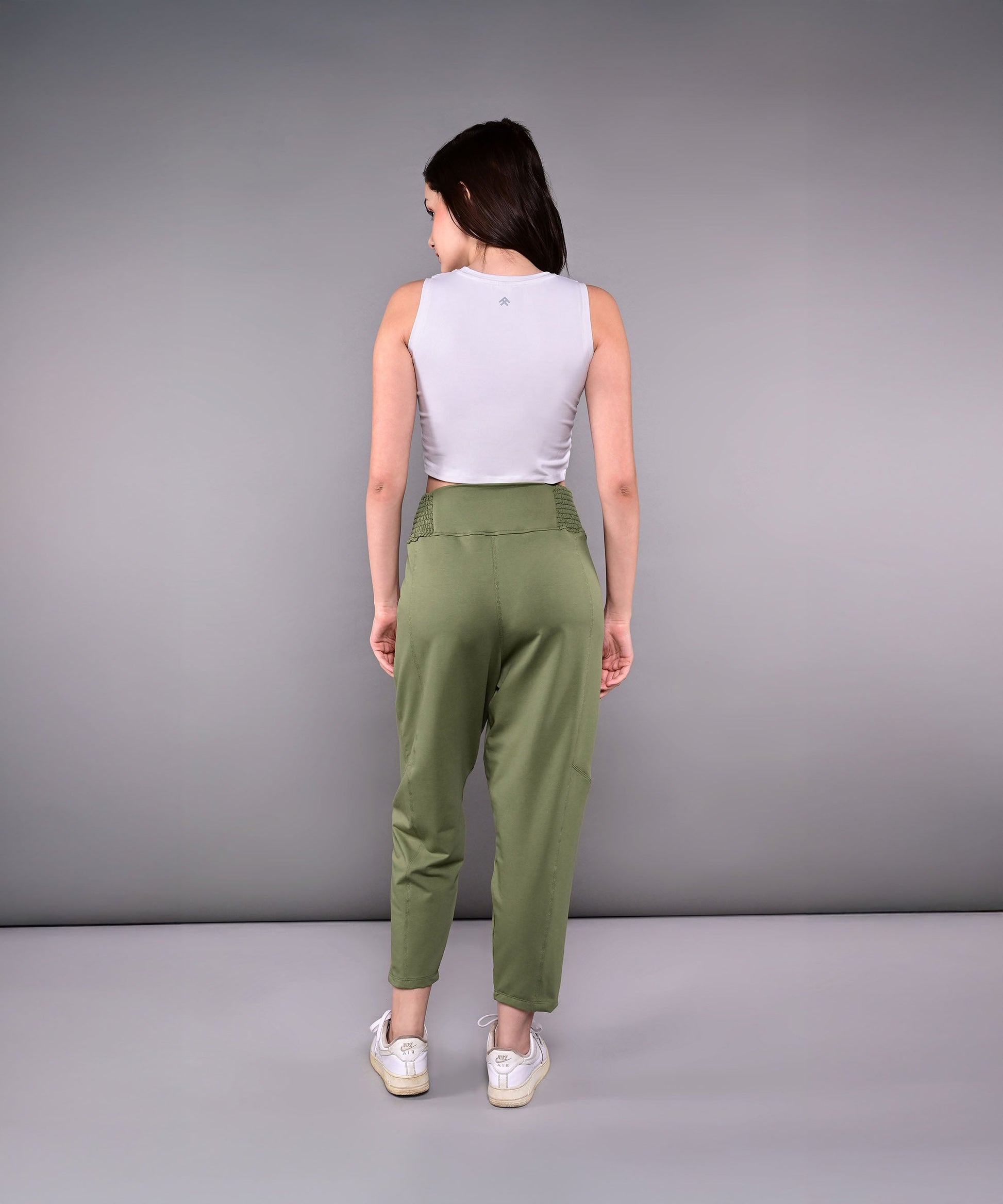 Back view of stylish yoga pants with pockets in olive green paired with a fitted gray tank top