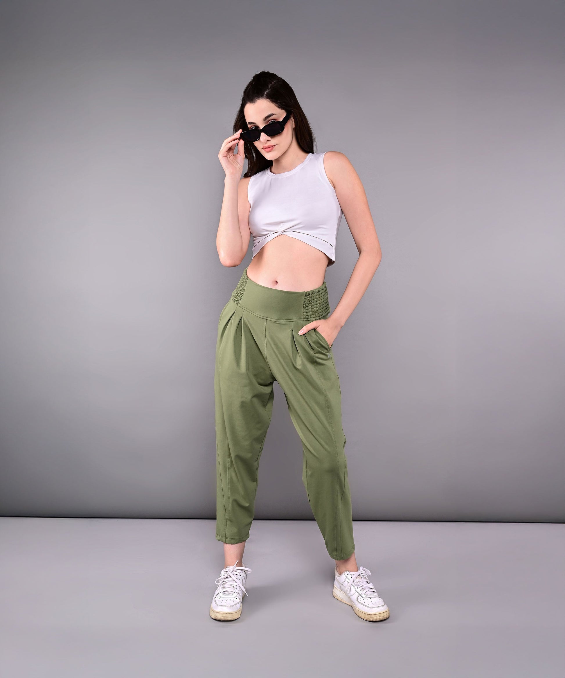 Fashionable model wearing stylish yoga pants with pockets in olive green and a white crop top