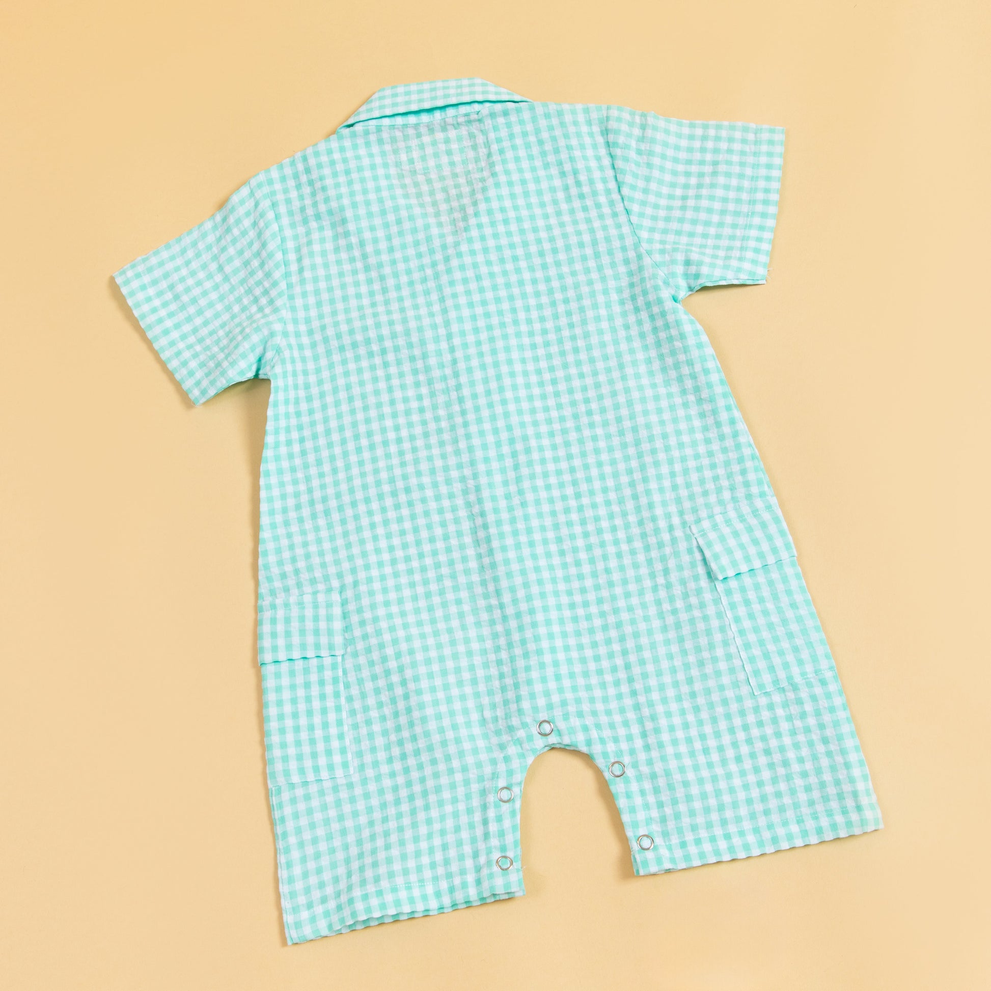 Back view of a teal summer gingham romper outfit with short sleeves and snap closures