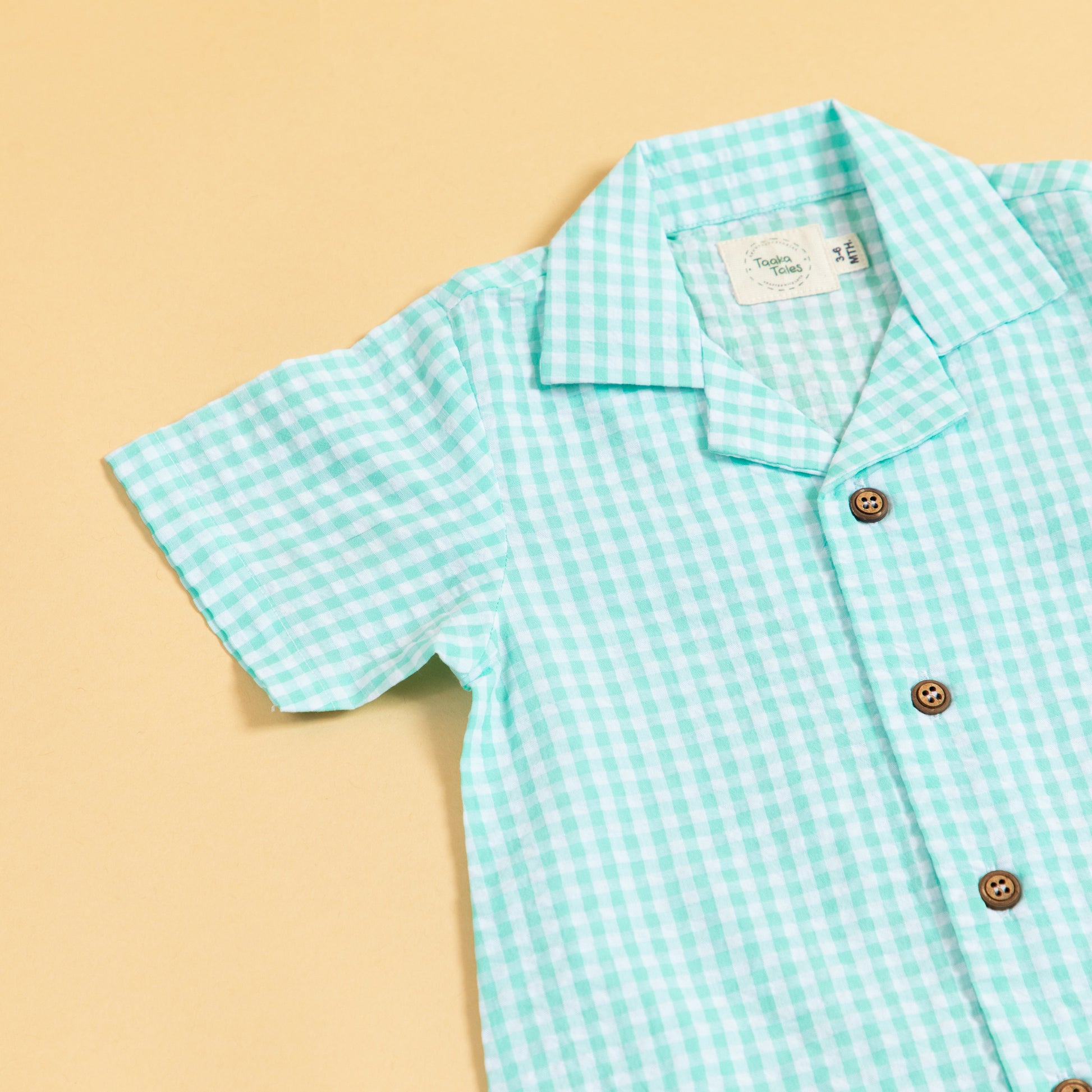 Light green and white summer gingham romper outfit with short sleeves and button details
