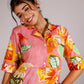 Woman wearing a summer pink cotton dress with vibrant floral patterns and a button-up design
