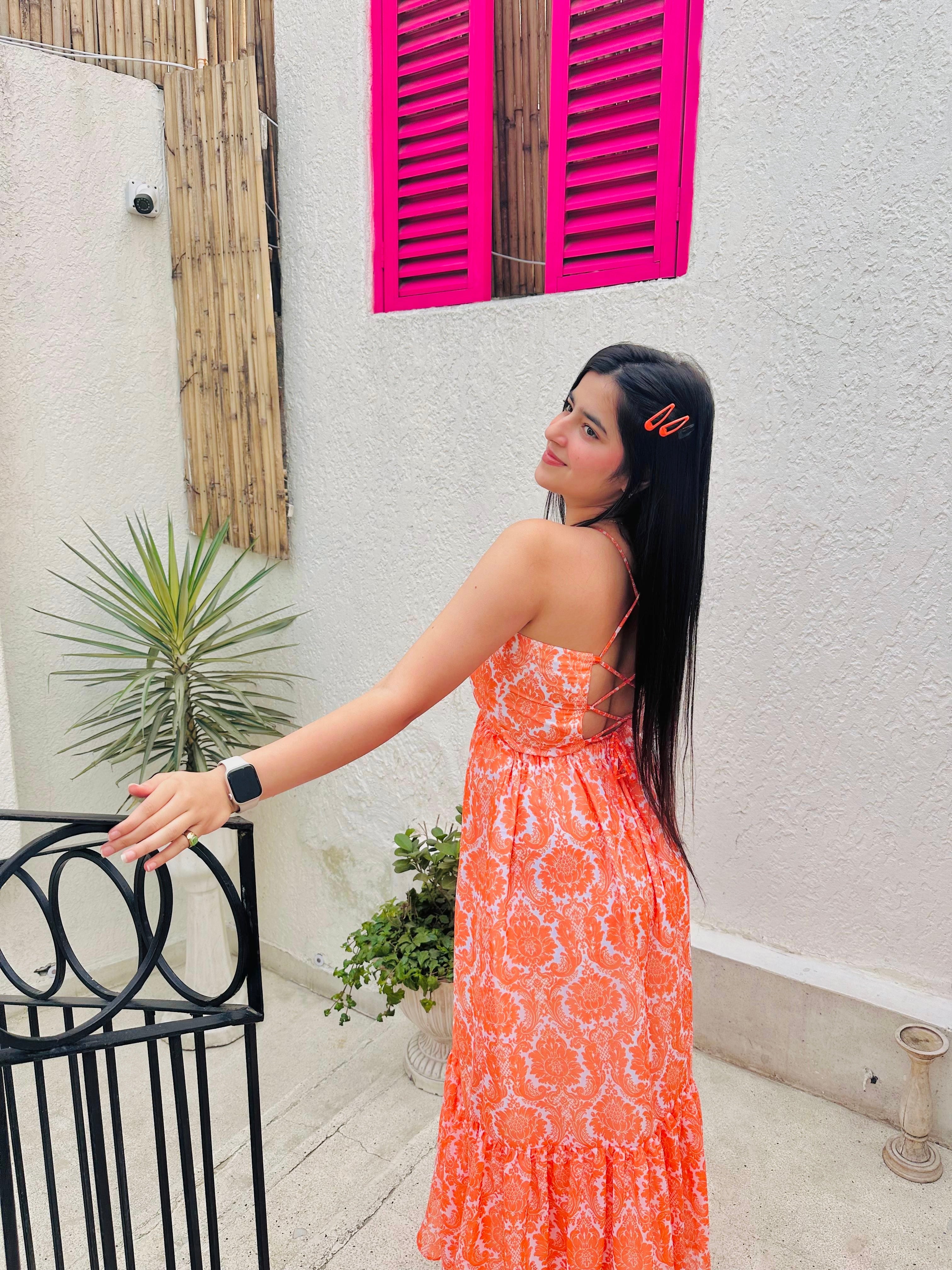 Stylera Muse casual backless maxi dress in orange paisley print worn by model outdoors showing strappy back and flowy hem