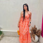 Woman in orange patterned casual backless maxi dress with yellow woven bag and matching sandals in courtyard