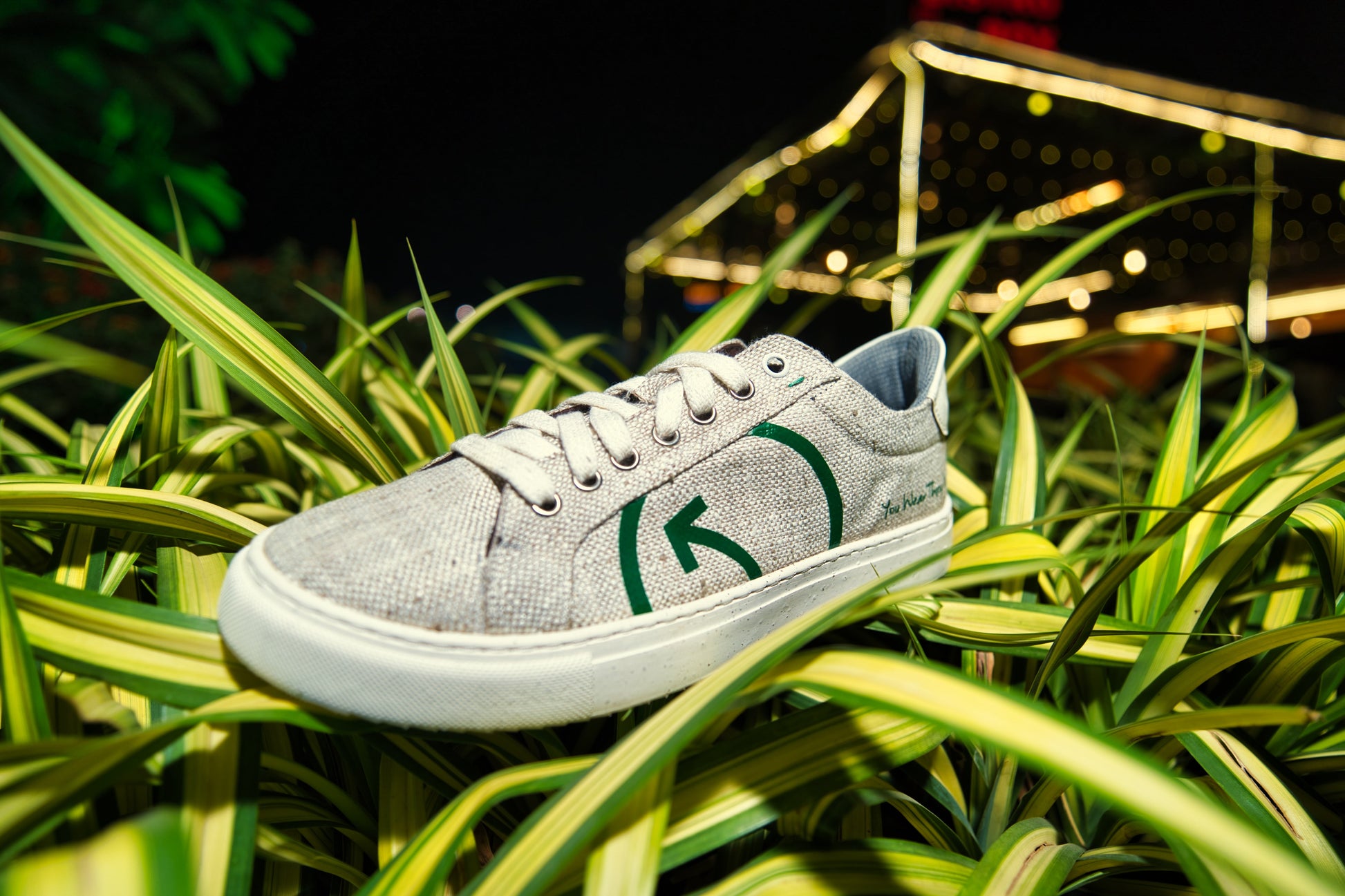 Stylish Stylera sustainable fashion sneakers for women on green grass under colorful lights