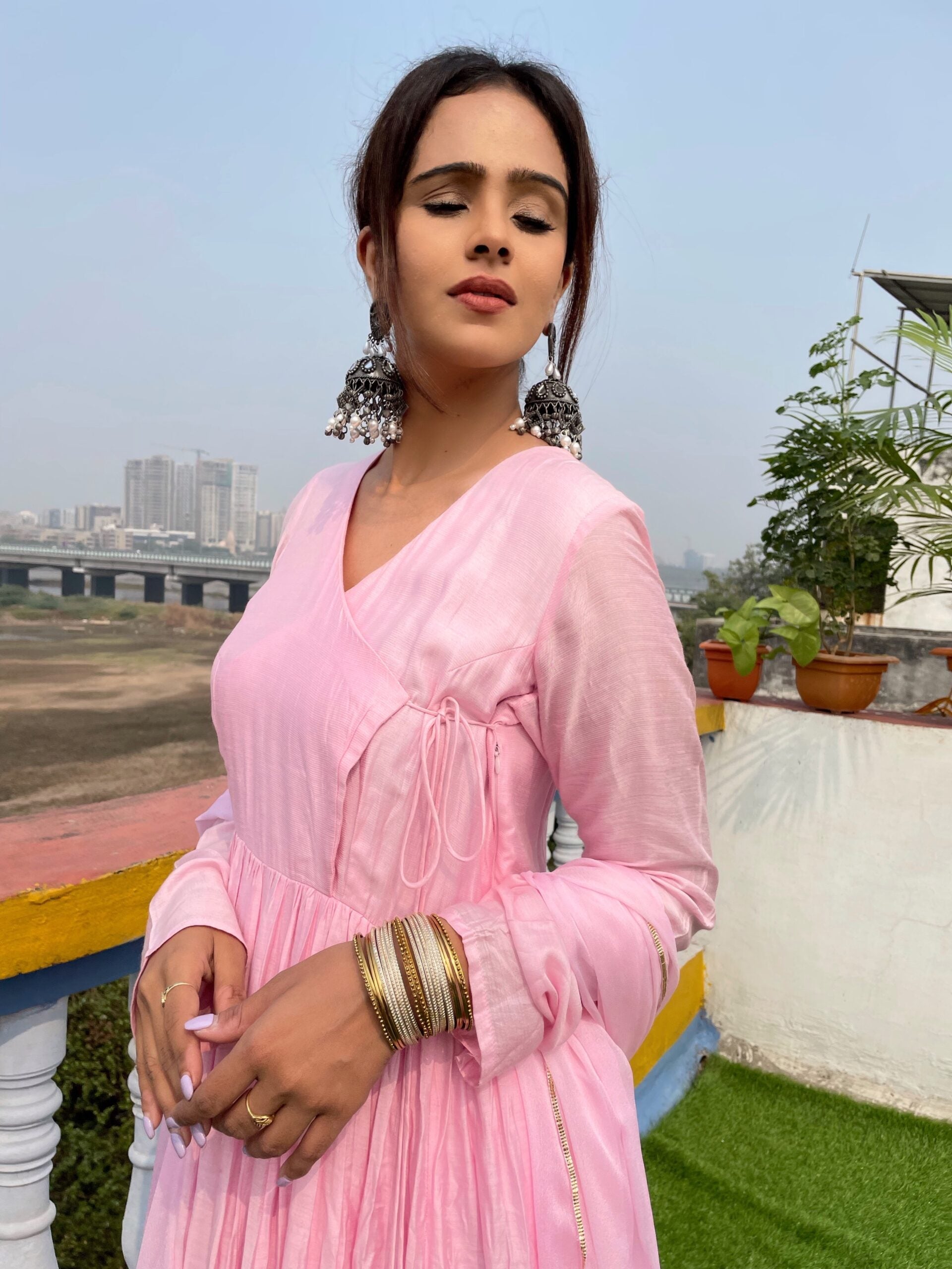 Elegant model wearing a taffy pink anarkali suit set with beautiful earrings and bangles