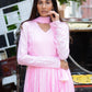 Model wearing a taffy pink anarkali suit set with elegant pleats and matching dupatta in a street setting