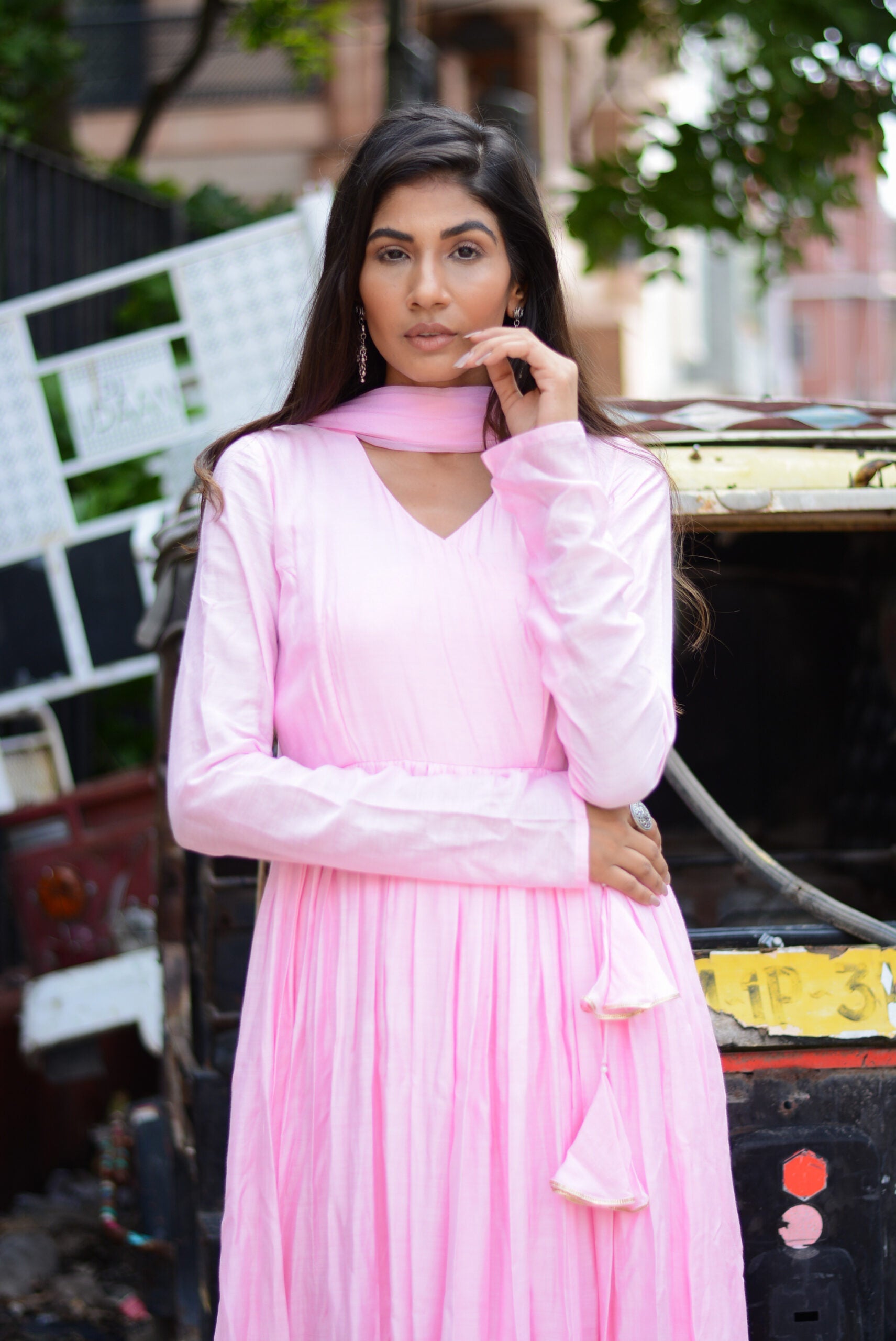 Model wearing a taffy pink anarkali suit set with elegant pleats and matching dupatta in a street setting