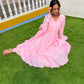 Model wearing a taffy pink anarkali suit set with pleated design on a green lawn
