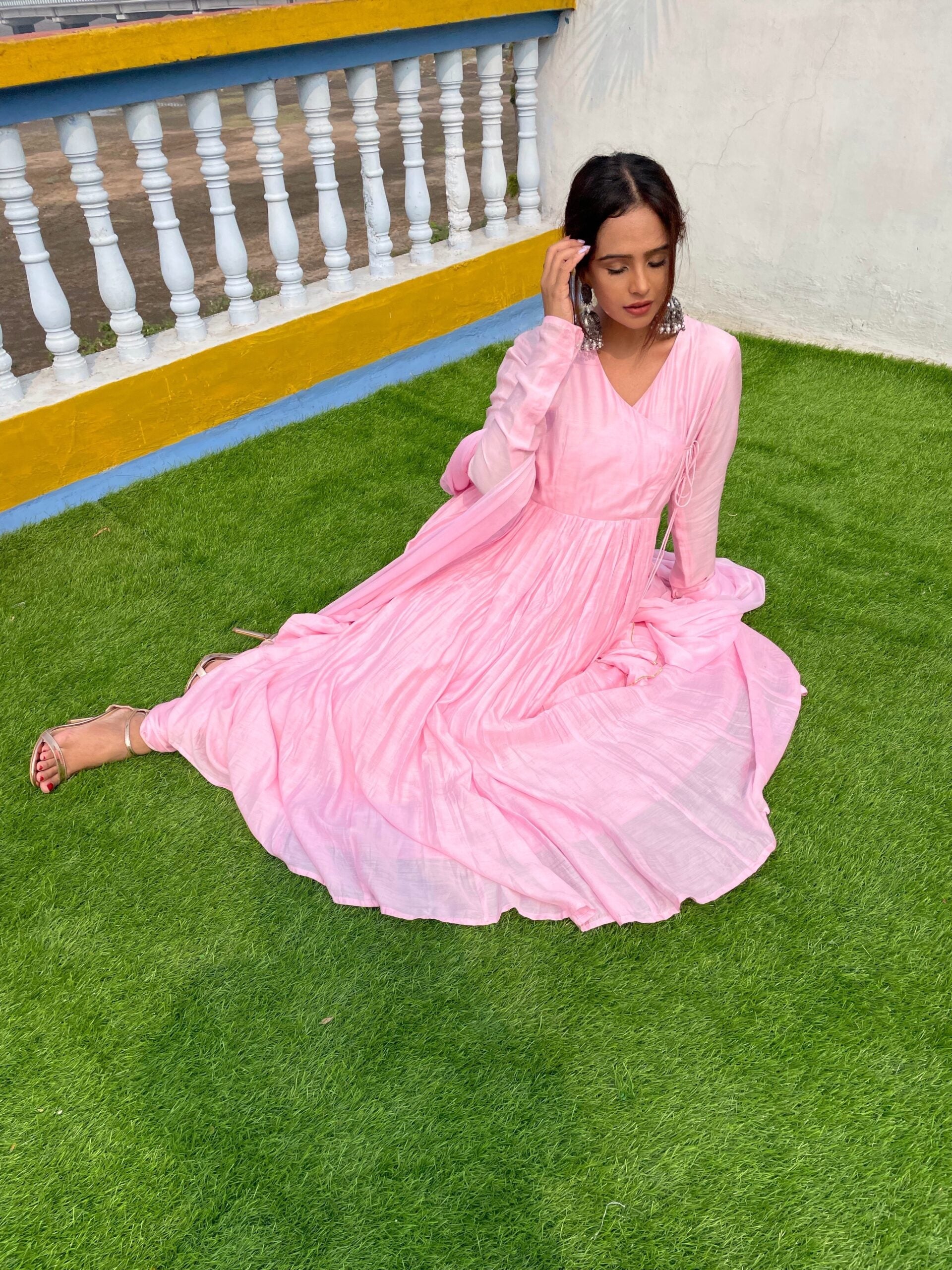 Model wearing a taffy pink anarkali suit set with pleated design on a green lawn