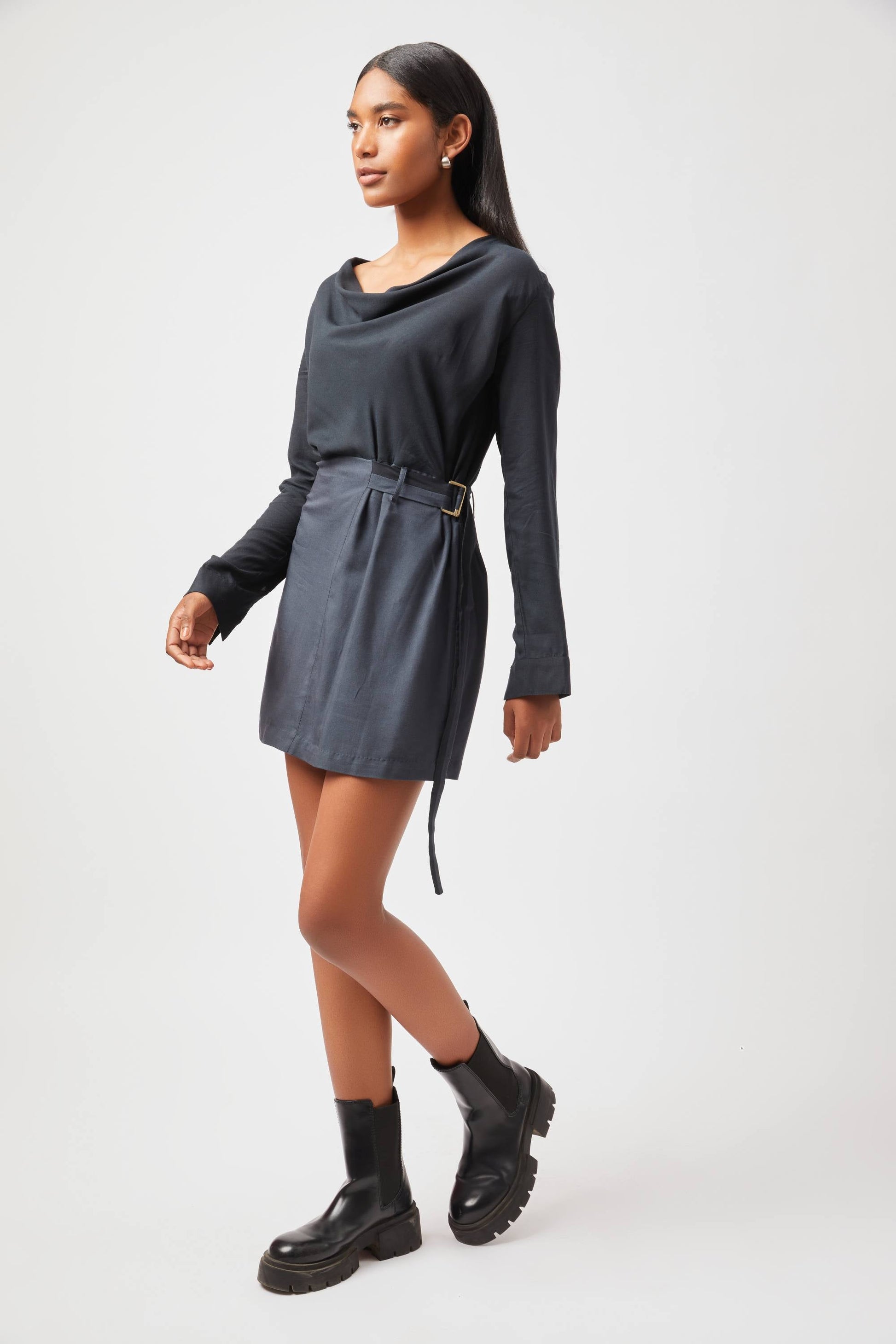 Stylera Tate cowl neck dress in black with long sleeves and belt worn with black boots