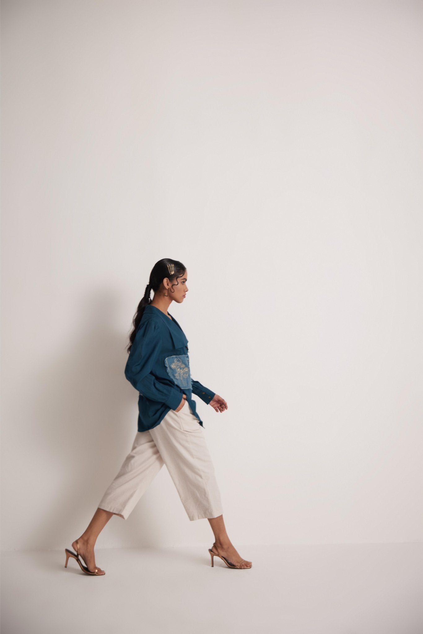 Woman wearing a teal cotton shirt for women with embroidery by Stylera walking in beige pants