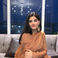 Stylish model in a traditional Anarkali gown caramel, posing elegantly in a modern setting