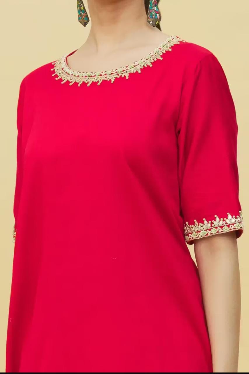 Woman wearing traditional red suit with embroidery featuring gold neckline and sleeve trim suitable for festive occasions