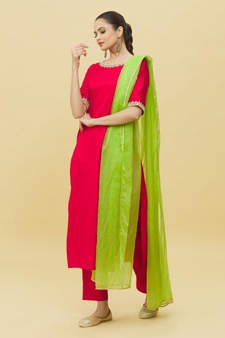 Model wearing traditional red suit with embroidery paired with lime green dupatta and straight pants for festive occasions