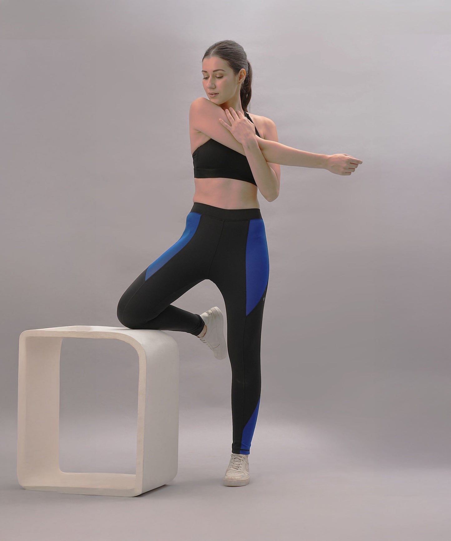 Trendy black blue athletic pants designed for active wear, showcased by a model stretching
