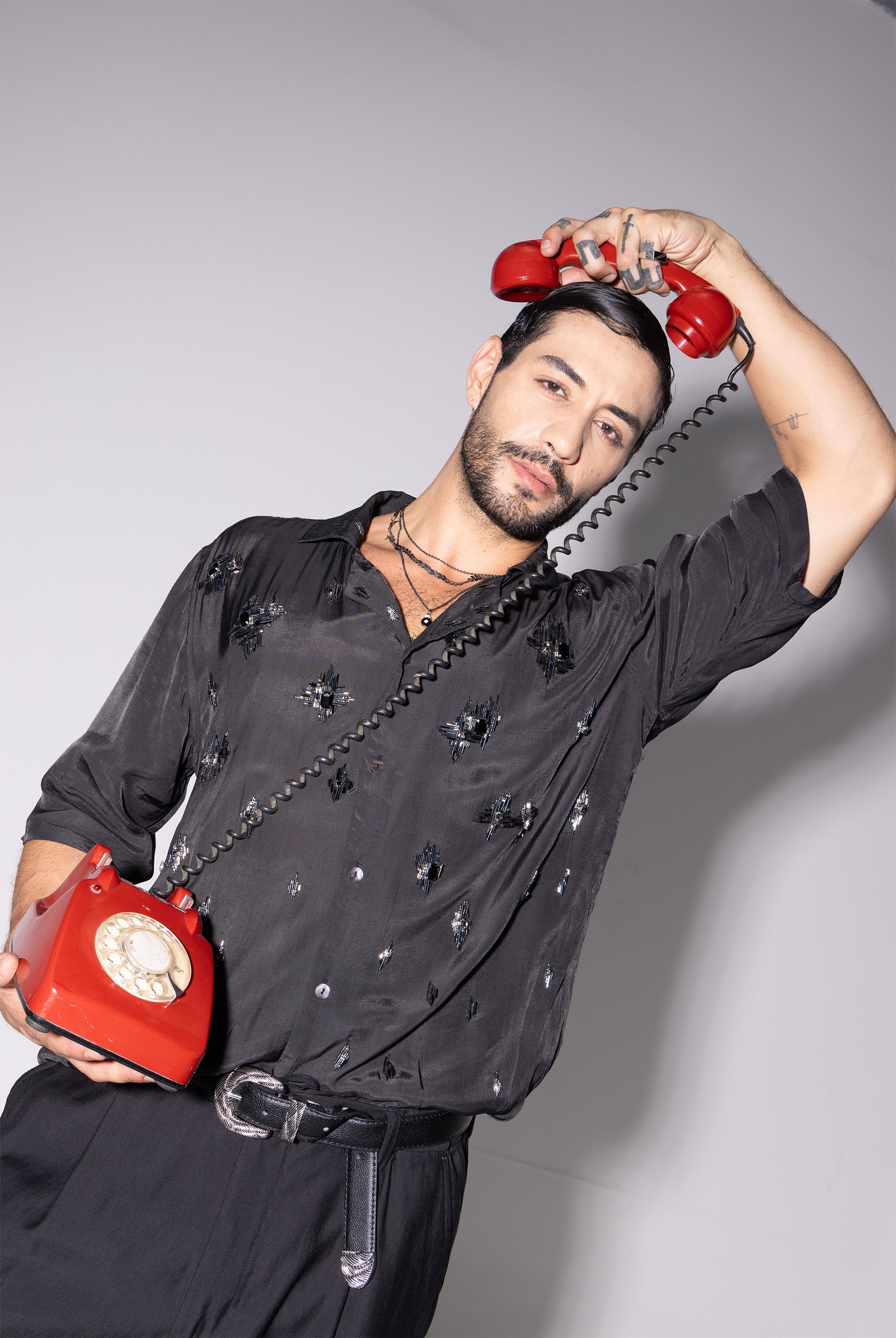 Stylish model wearing a trendy black men's fashion shirt with a vintage red phone