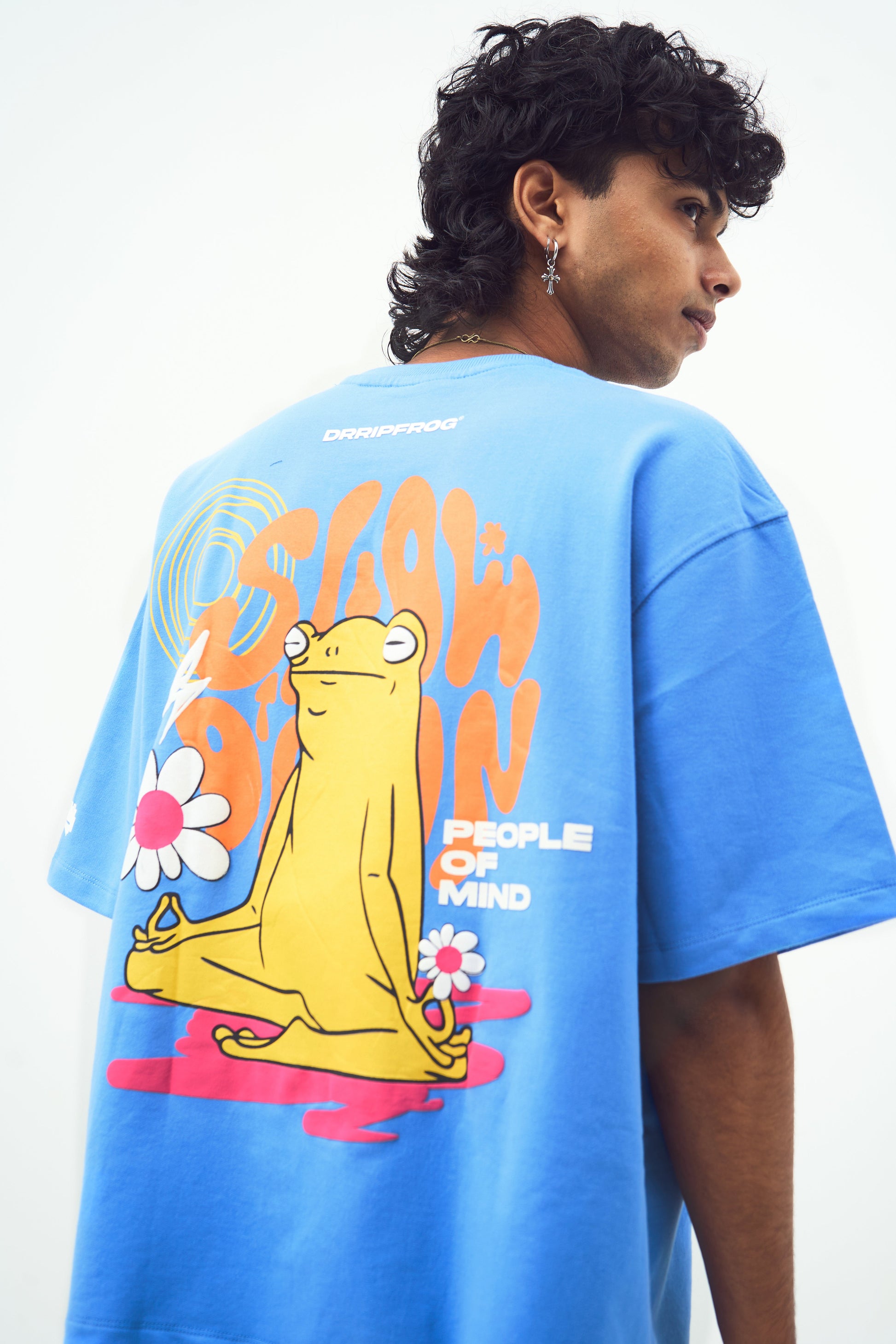 Model wearing Stylera trendy blue t-shirt for men and women with large back meditating frog and flowers