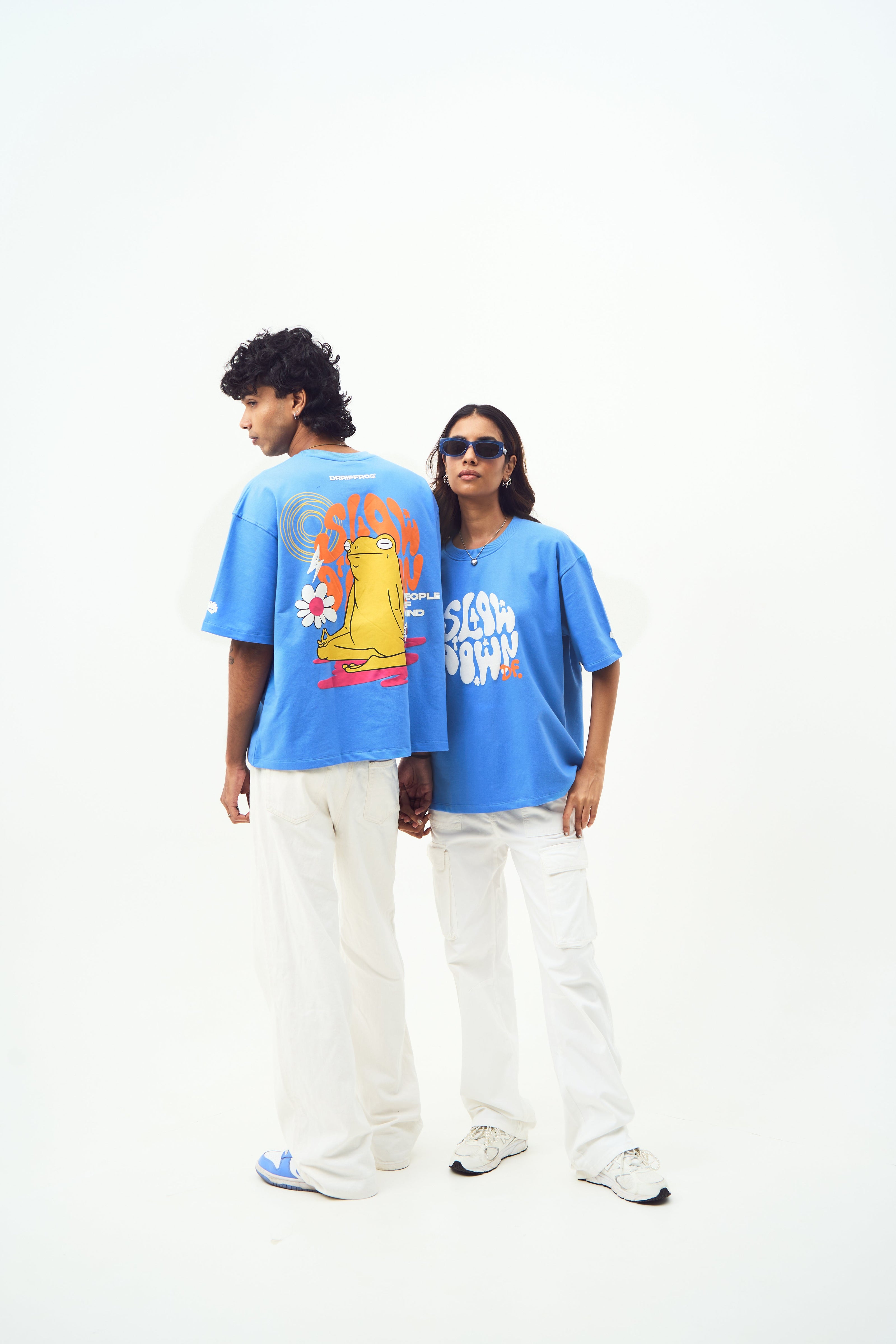 Two models wearing Stylera trendy blue t-shirt for men and women with graphic back print and white pants
