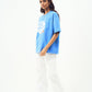 Female model wearing Stylera trendy blue t-shirt for men and women oversized fit with white cargo pants