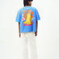 Back view of model wearing trendy blue t-shirt for men and women by Stylera with yellow frog print and relaxed fit