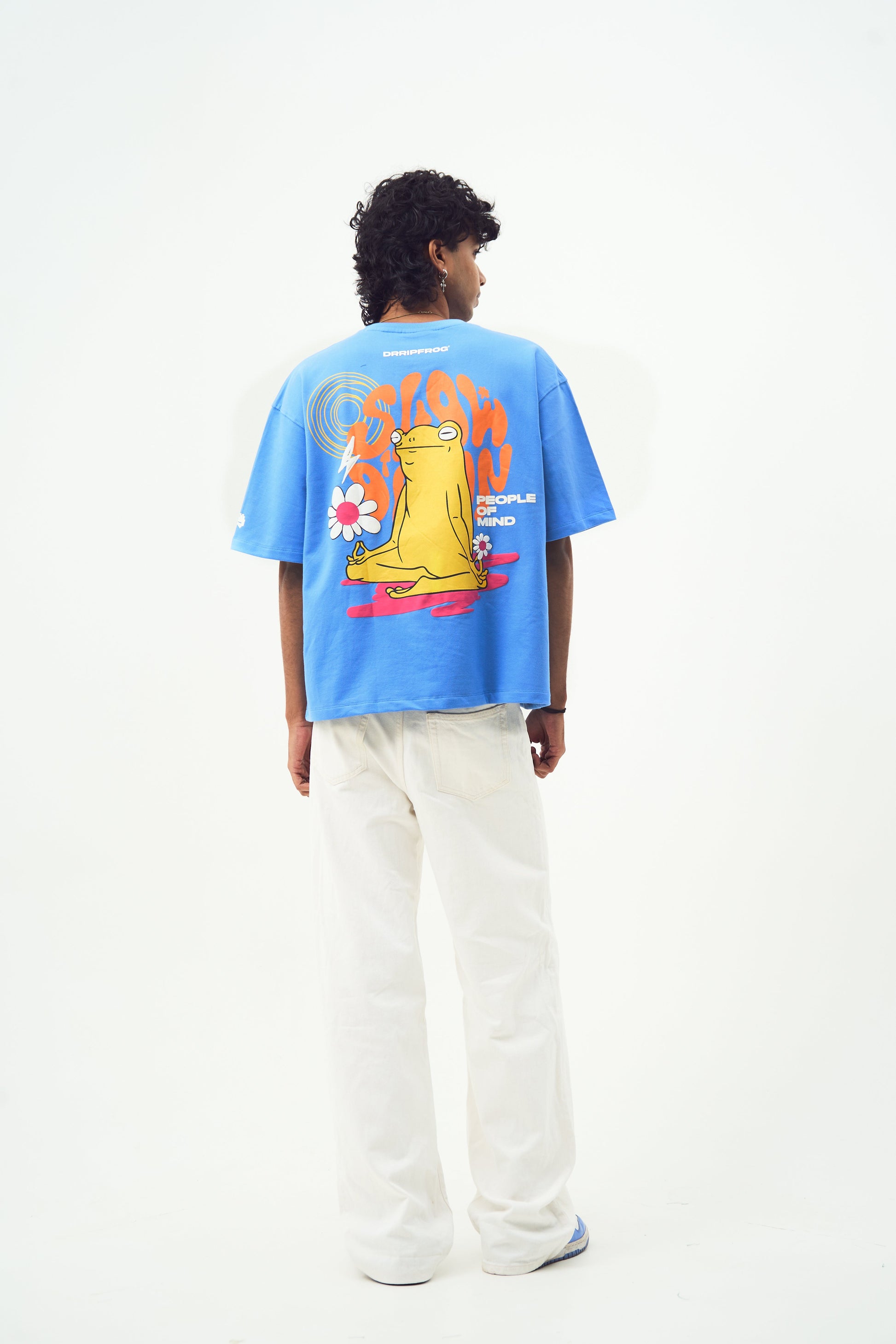 Back view of model wearing trendy blue t-shirt for men and women by Stylera with yellow frog print and relaxed fit
