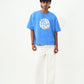 Male model wearing Stylera trendy blue t-shirt for men and women with white graphic print relaxed fit and white pants