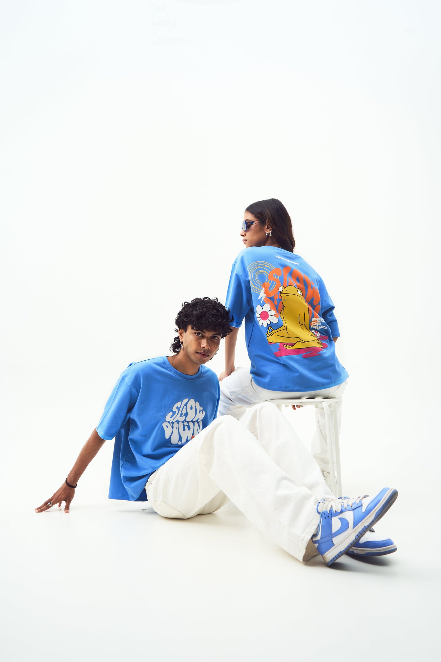 Stylera models wearing trendy blue t-shirt for men and women with bold graphic back print and white pants