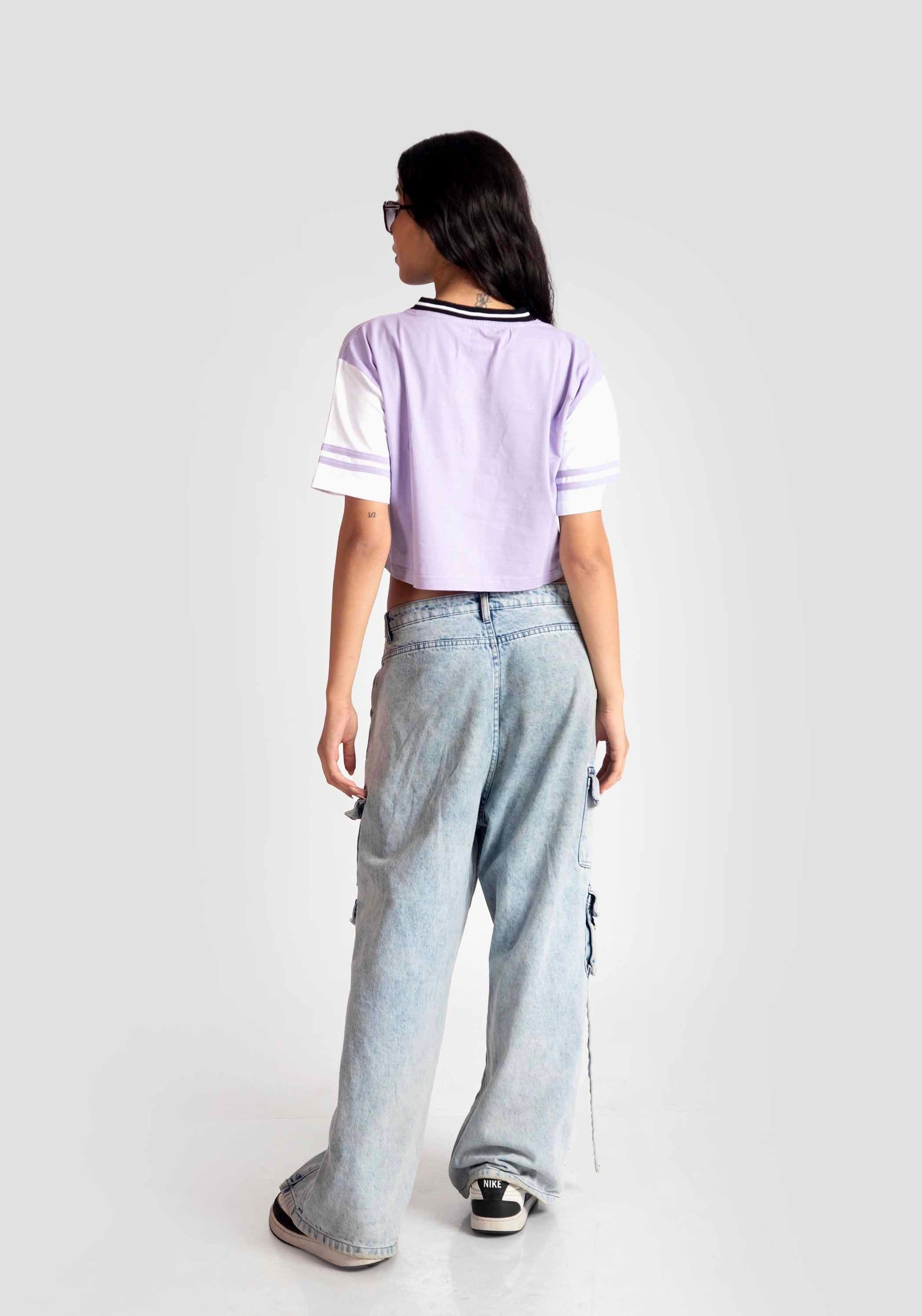 Back view of a woman wearing trendy casual tops for women in lavender and white paired with wide-leg jeans