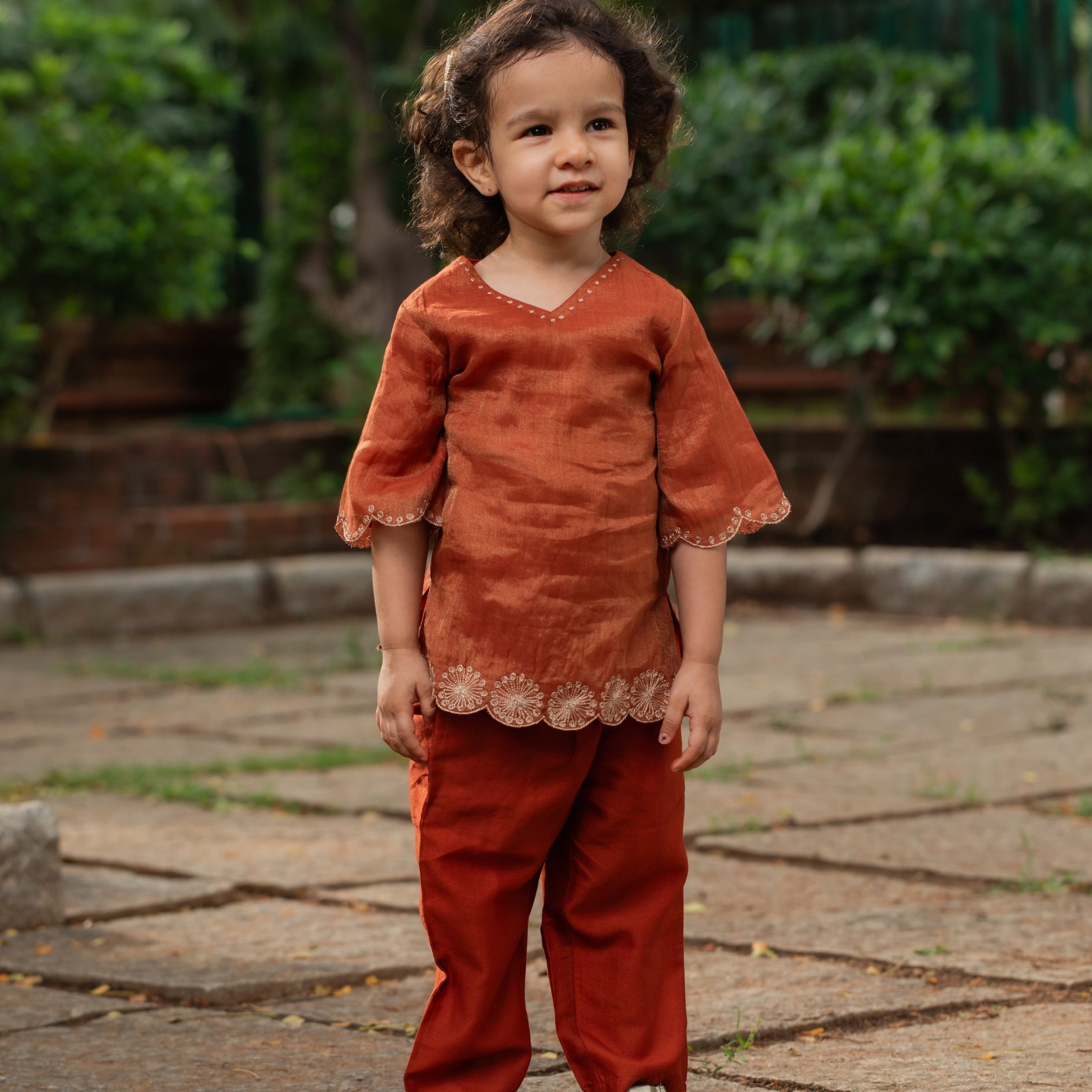 Cute child wearing a trendy children's ethnic outfit in rust color with detailed embroidery