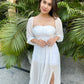 Model wearing a trendy evening maxi dress with a thigh-high slit against a tropical background