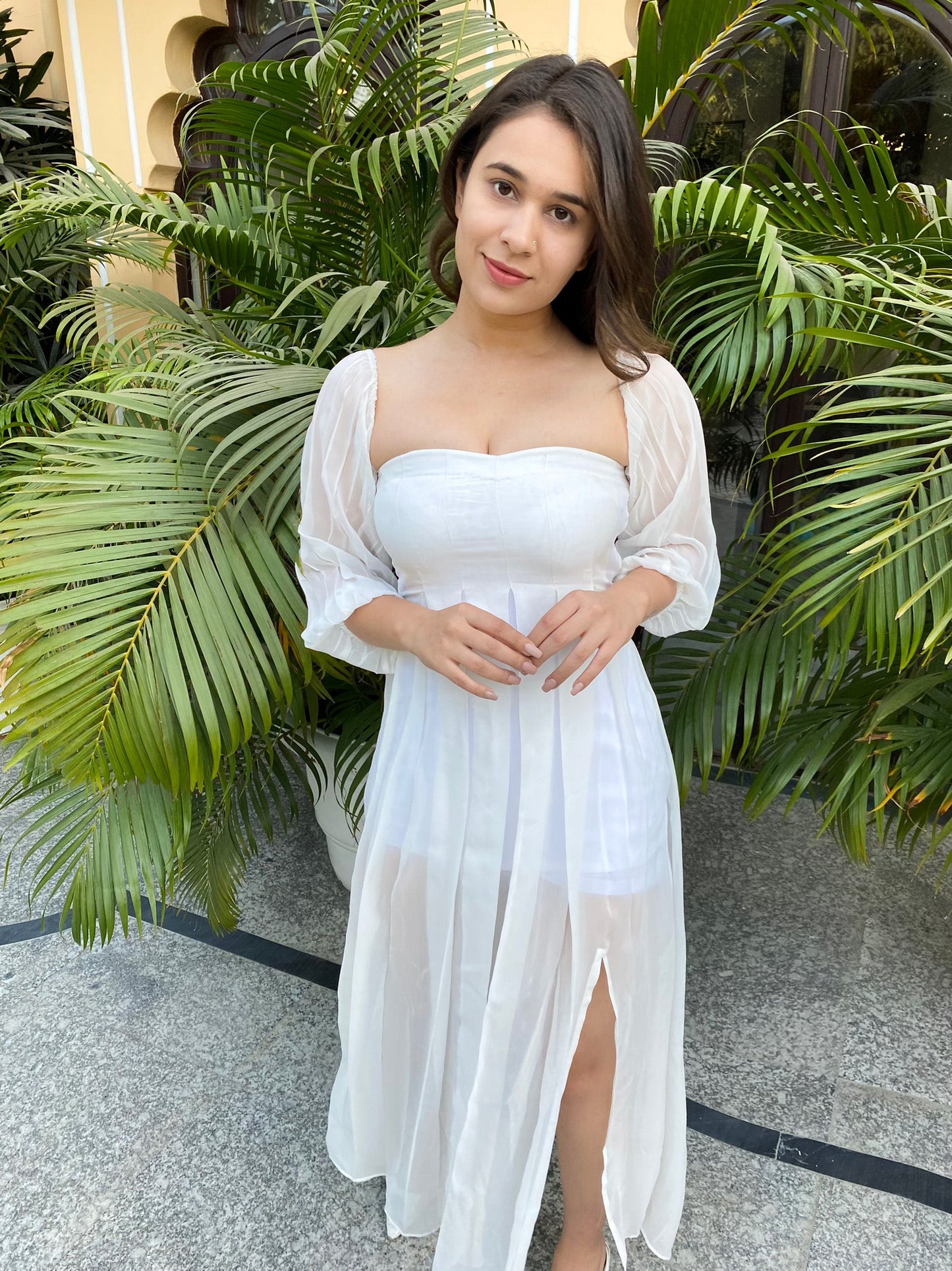 Model wearing a trendy evening maxi dress with a thigh-high slit against a tropical background