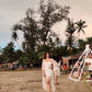 Model wearing a trendy evening maxi dress with a flowing design on the beach surrounded by palm trees