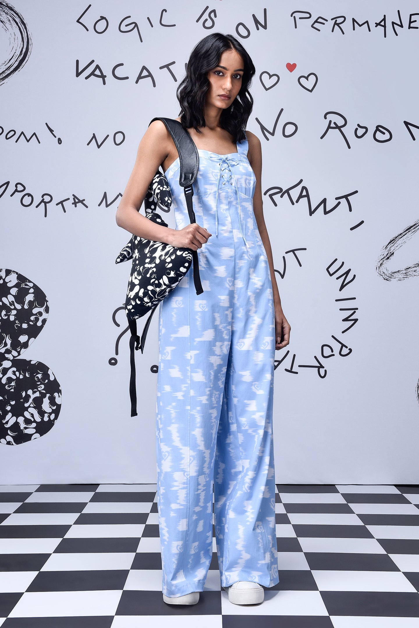 Stylera trendy ikat print jumpsuit in light blue worn with black and white backpack