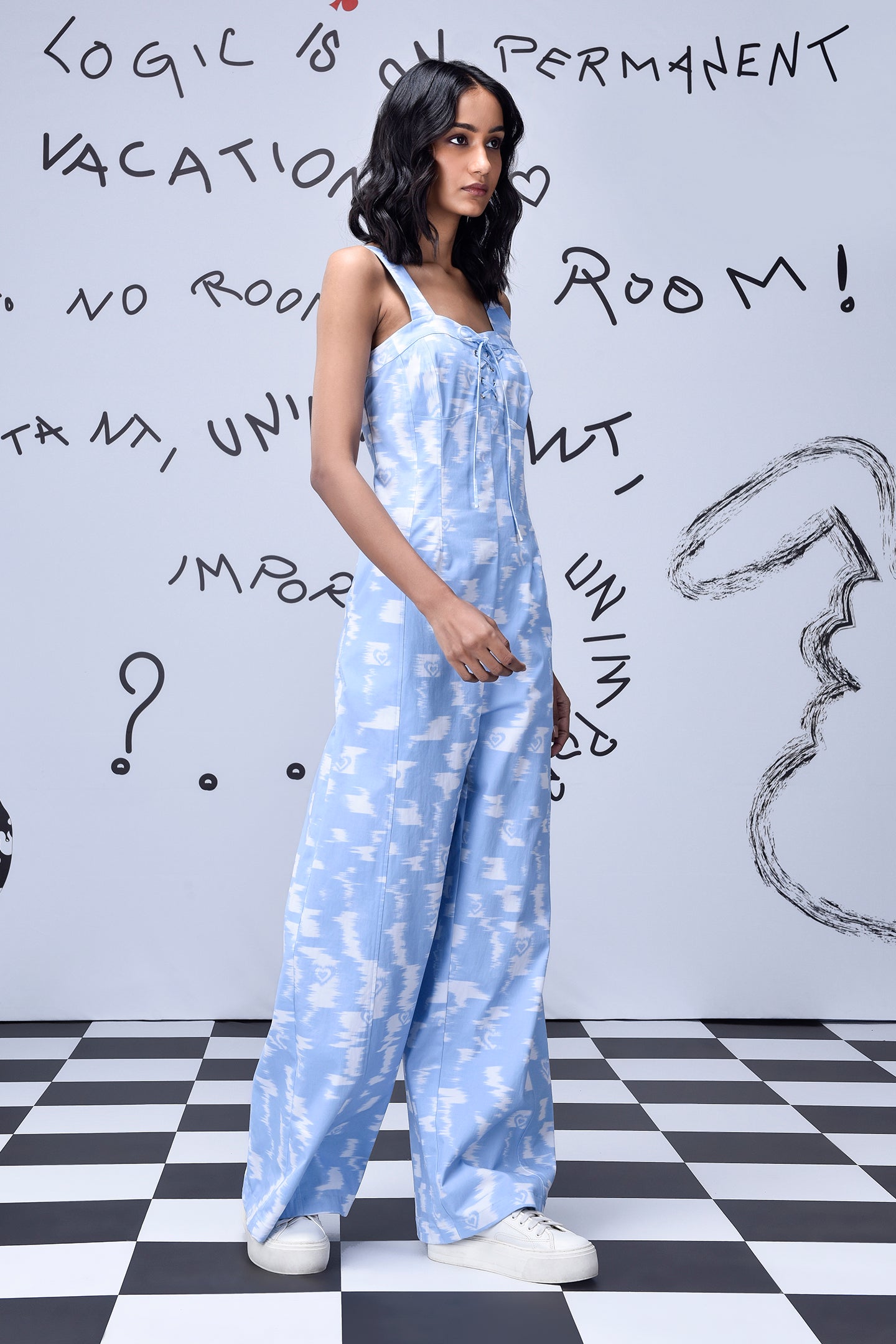 Stylera trendy ikat print jumpsuit in light blue with white sneakers on checkered floor