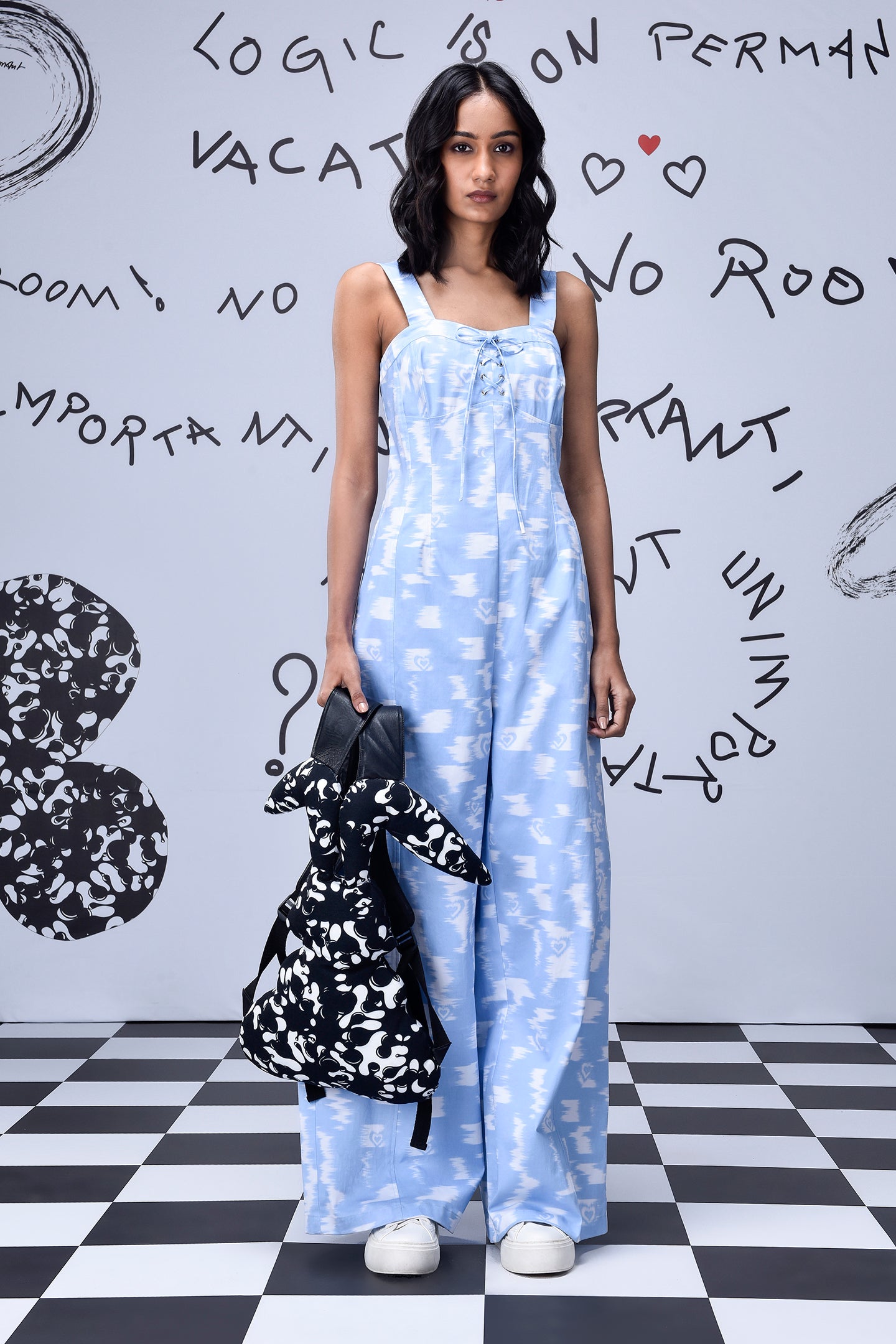 Stylera trendy ikat print jumpsuit in light blue worn by model with black and white backpack