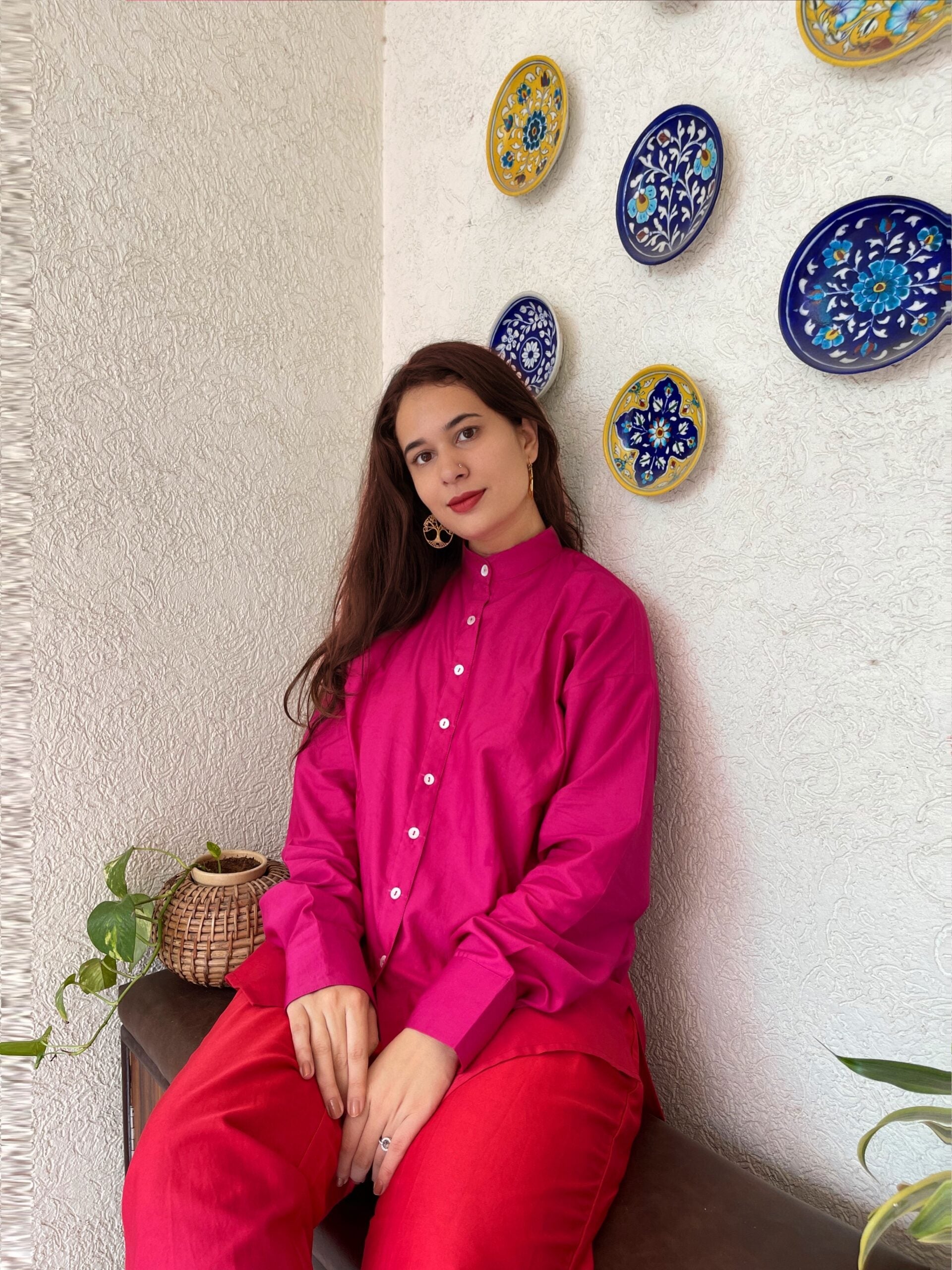 Trendy matching outfits for women featuring a bright pink shirt with red pants in a stylish setting