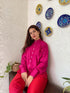 Trendy matching outfits for women featuring a bright pink shirt with red pants in a stylish setting